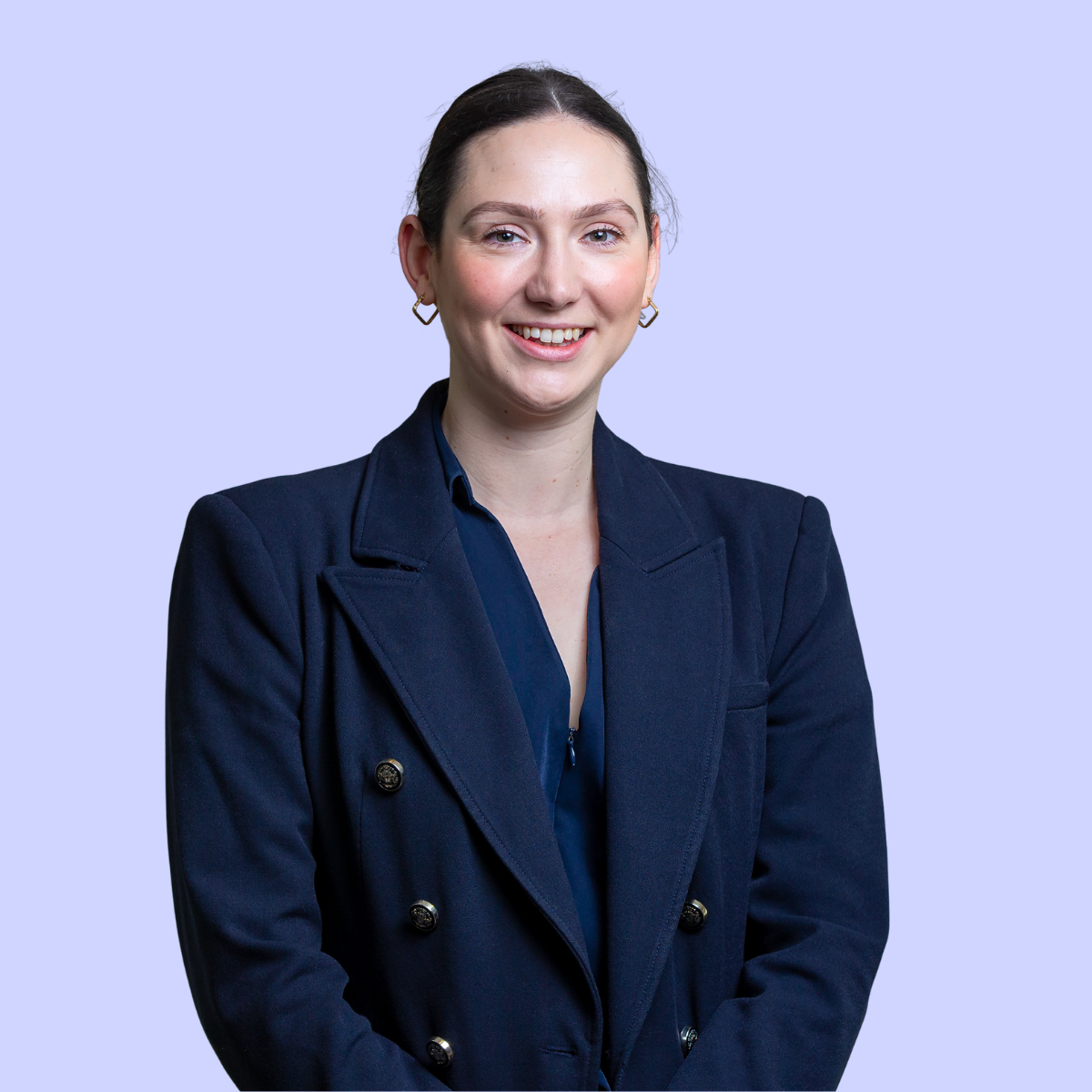 Jenny wearing a black polka dot dress standing against a light purple background.