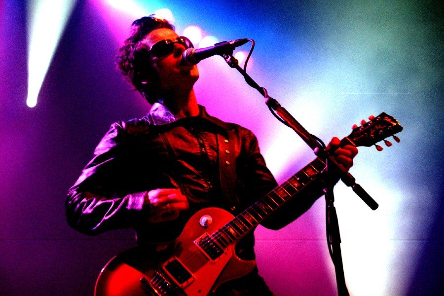 Musician playing guitar on stage with colorful lights