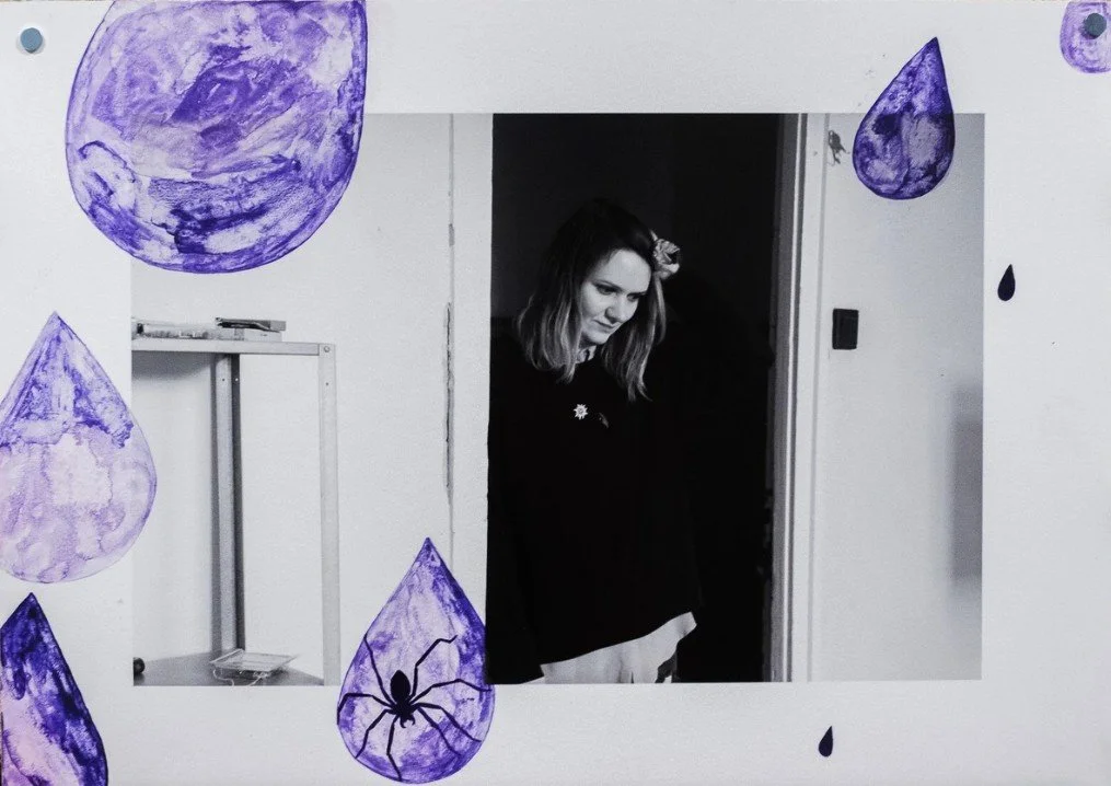 Black and white photo of a person standing in a doorway, wearing a dark sweatshirt, with their hand touching their head.