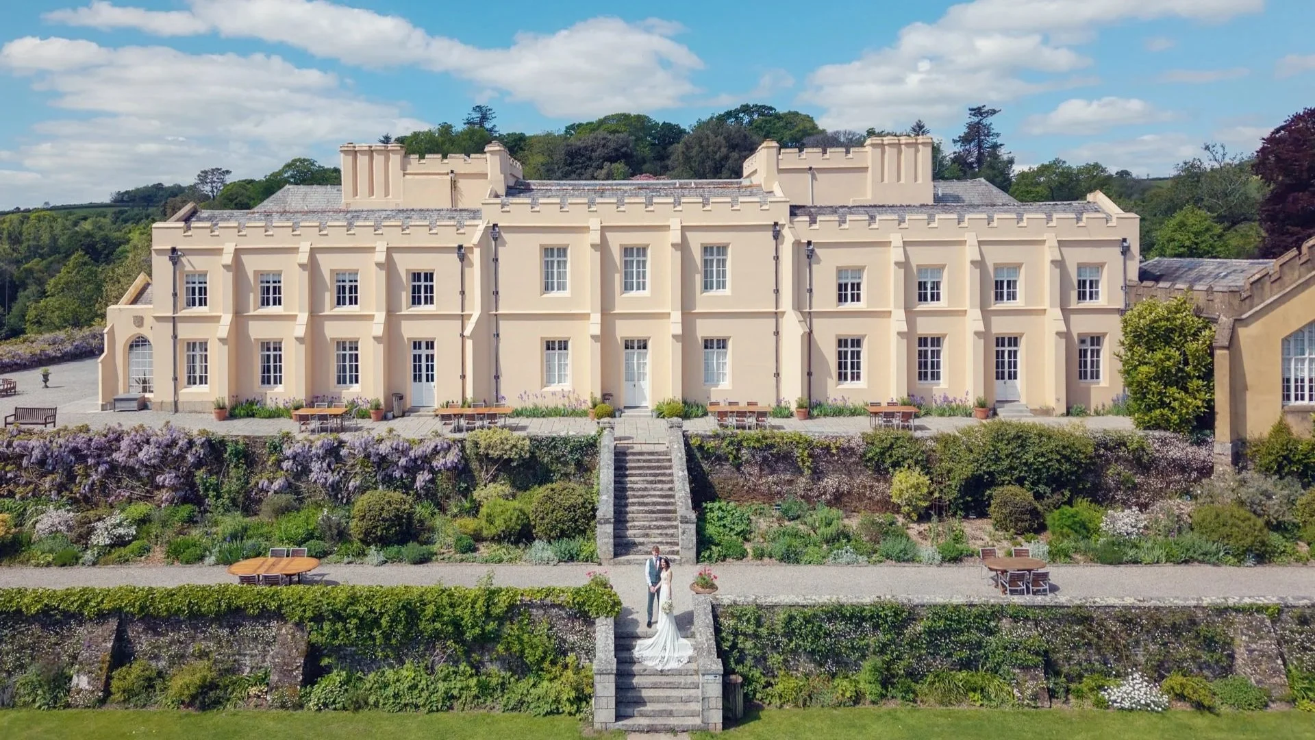 Bride and groom stood on the lower terrace stairs at Pentillie Castle.