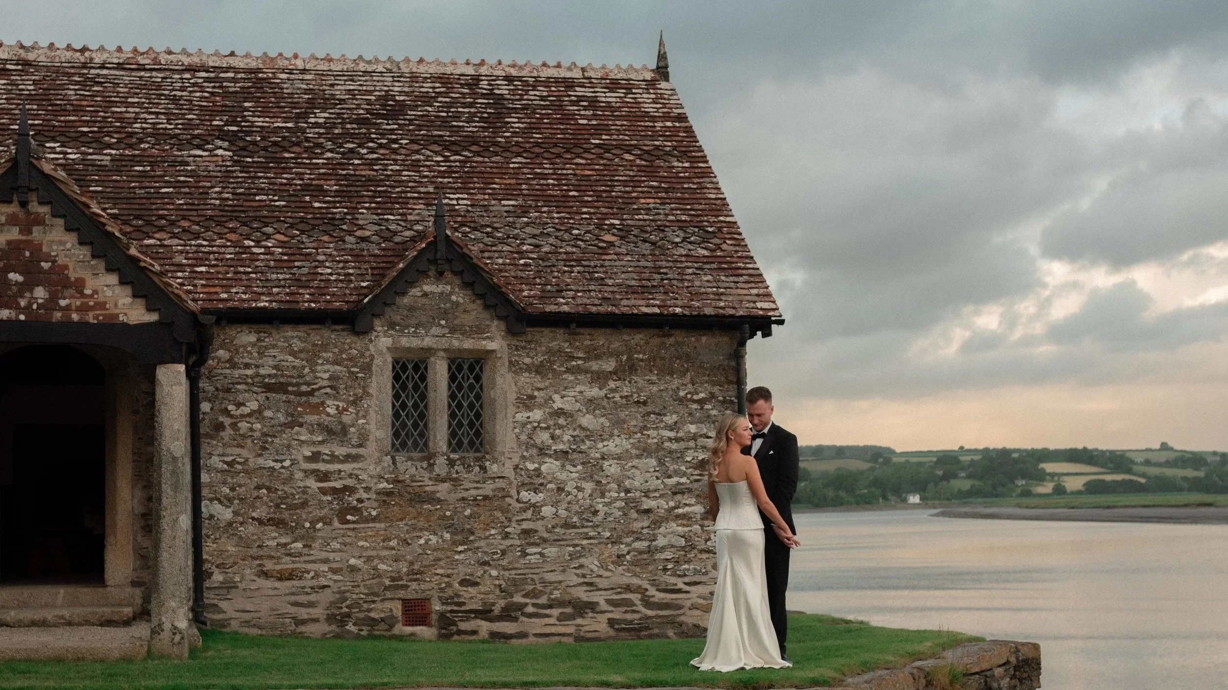 Bride & groom stood outside Bathing Hut at Pentillie Castle looking out to the River Tamar. Photographed by In Lovers Eyes.