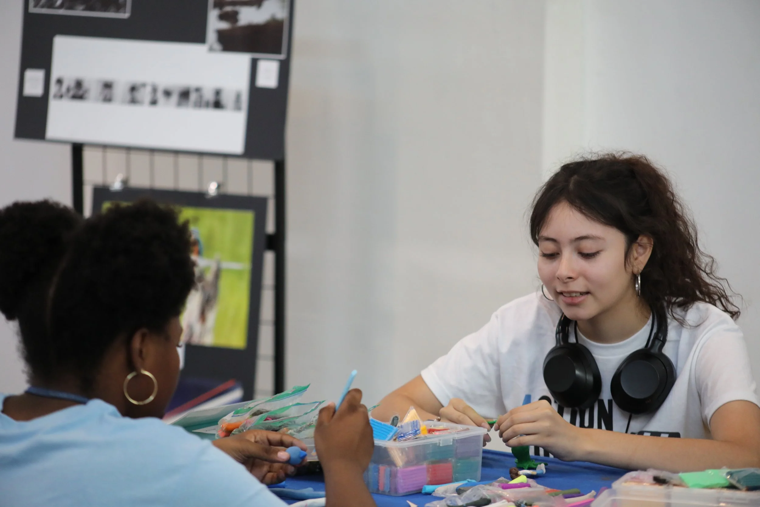 Two people at a table sculpting brightly colored clay. They are sitting across from each other.