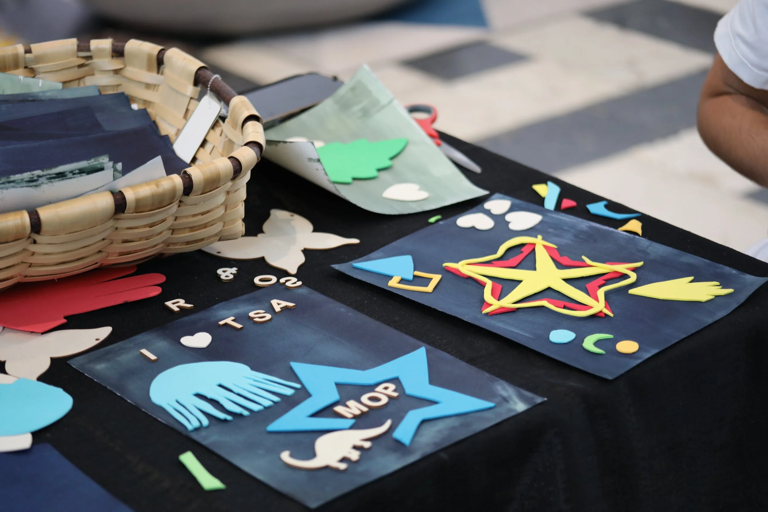 Two painted sheets of paper covered in brightly colored foam shapes and wooden cutouts. This is done to create a cyanotype photo.
