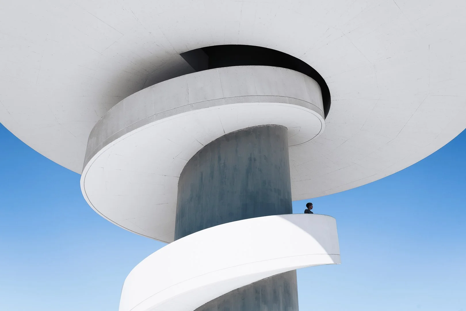Minimal photo of the white building and blue sky with a figure standing on the staircase