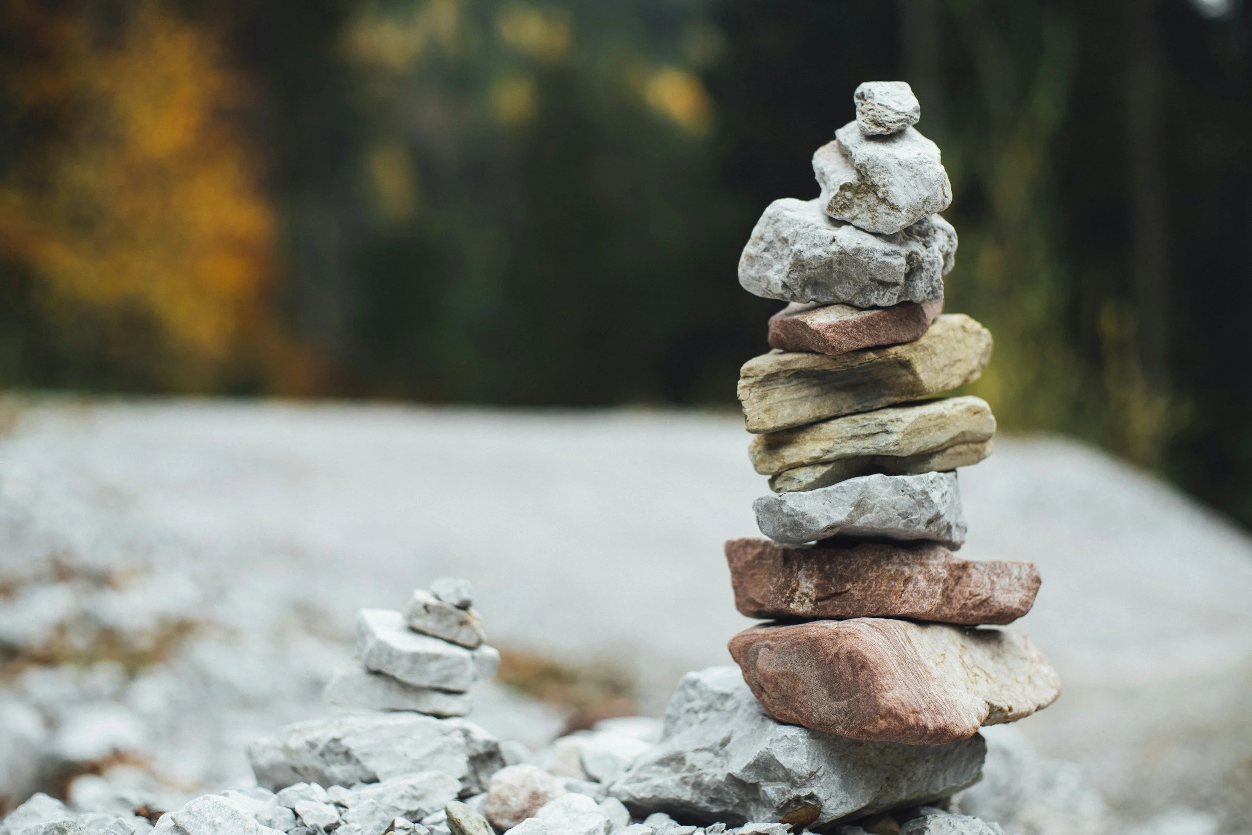 Stacked rocks of various sizes and colors balanced on a flat surface outdoors.