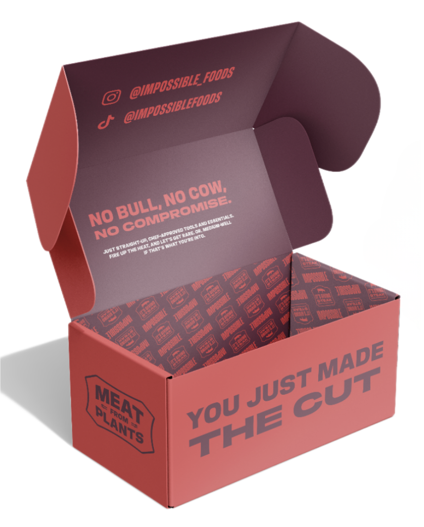Open cardboard box with the message "You just made the cut" printed on the front, and inside the box, there is branding for "Meat from D-Lants" and social media information, with the interior liner printed with the phrase "No bull. No cow. No compromise" and company branding.
