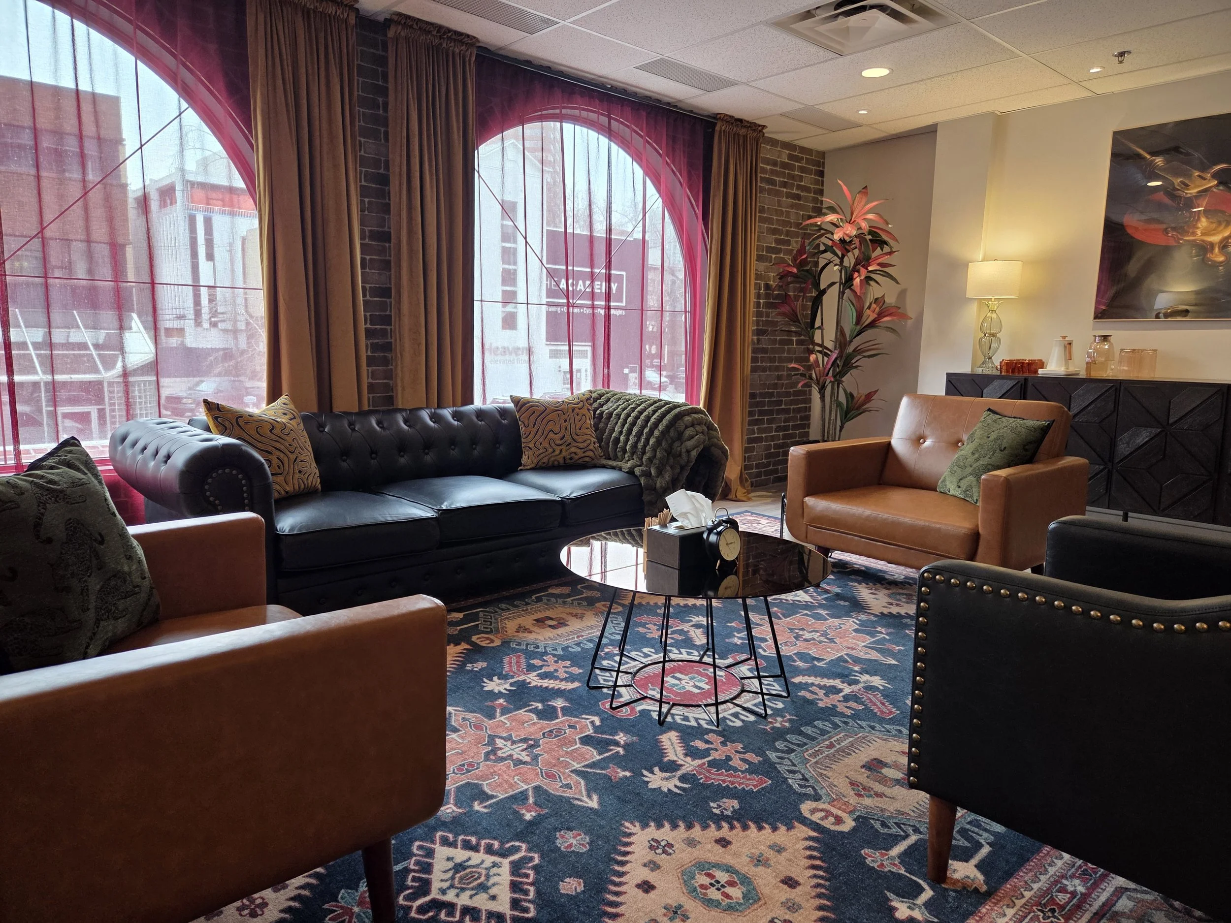 Modern therapy room with natural lighting, comfortable leather chairs, couch, and warm decor—private counselling space in Calgary for trauma, anxiety, and relationship therapy.