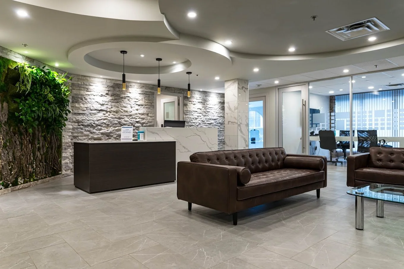 Modern therapy clinic reception area in Calgary with leather seating, stone accent wall, greenery, and welcoming front desk—professional counselling office environment.