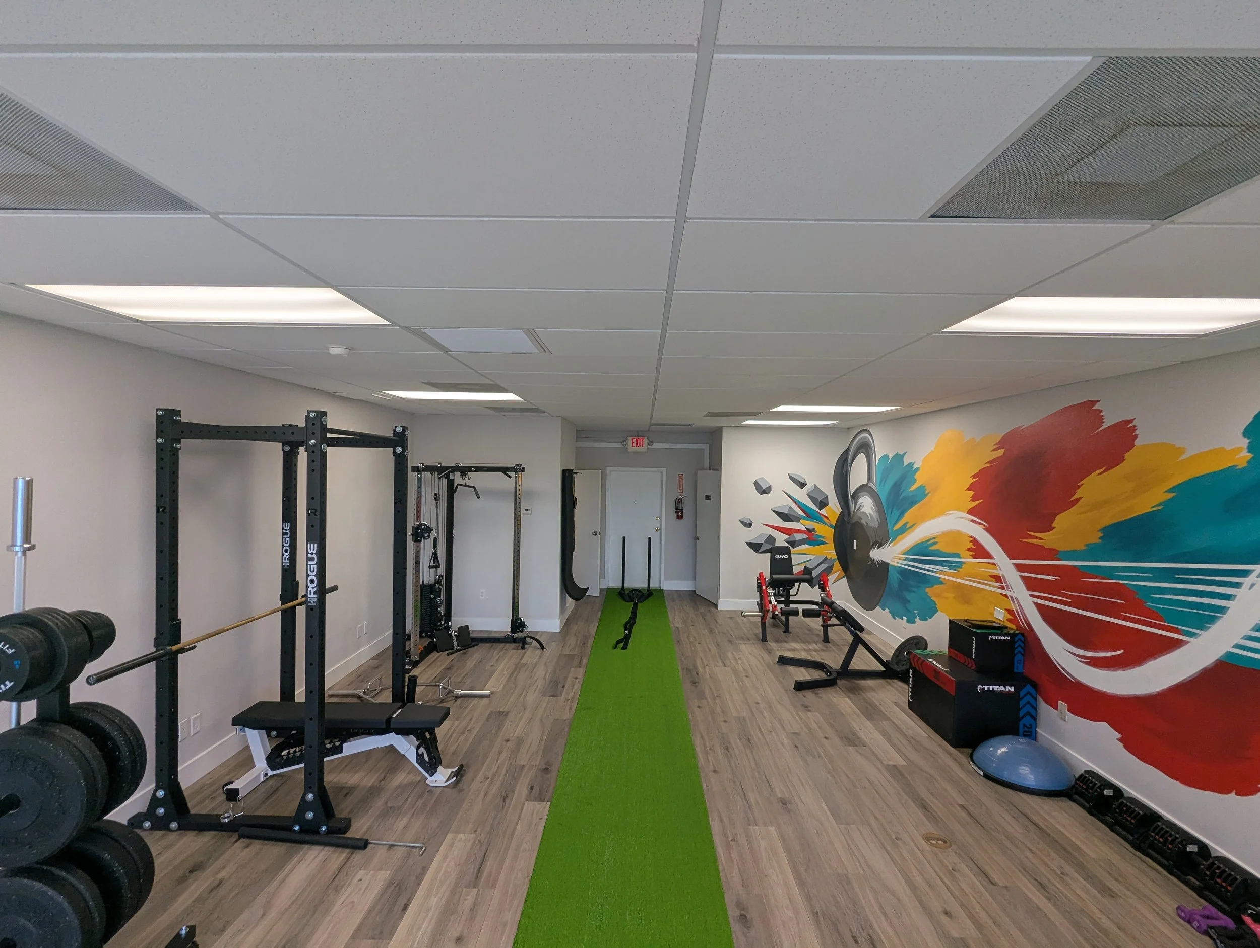 Private personal training studio in Fort Myers with squat racks, a turf lane and a colorful mural