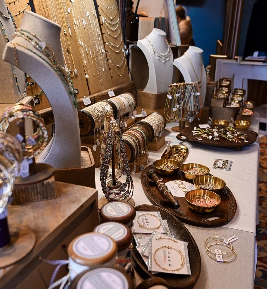 Table display of jewelry including necklaces, bracelets, rings, and earrings in a jewelry store or craft fair setting.