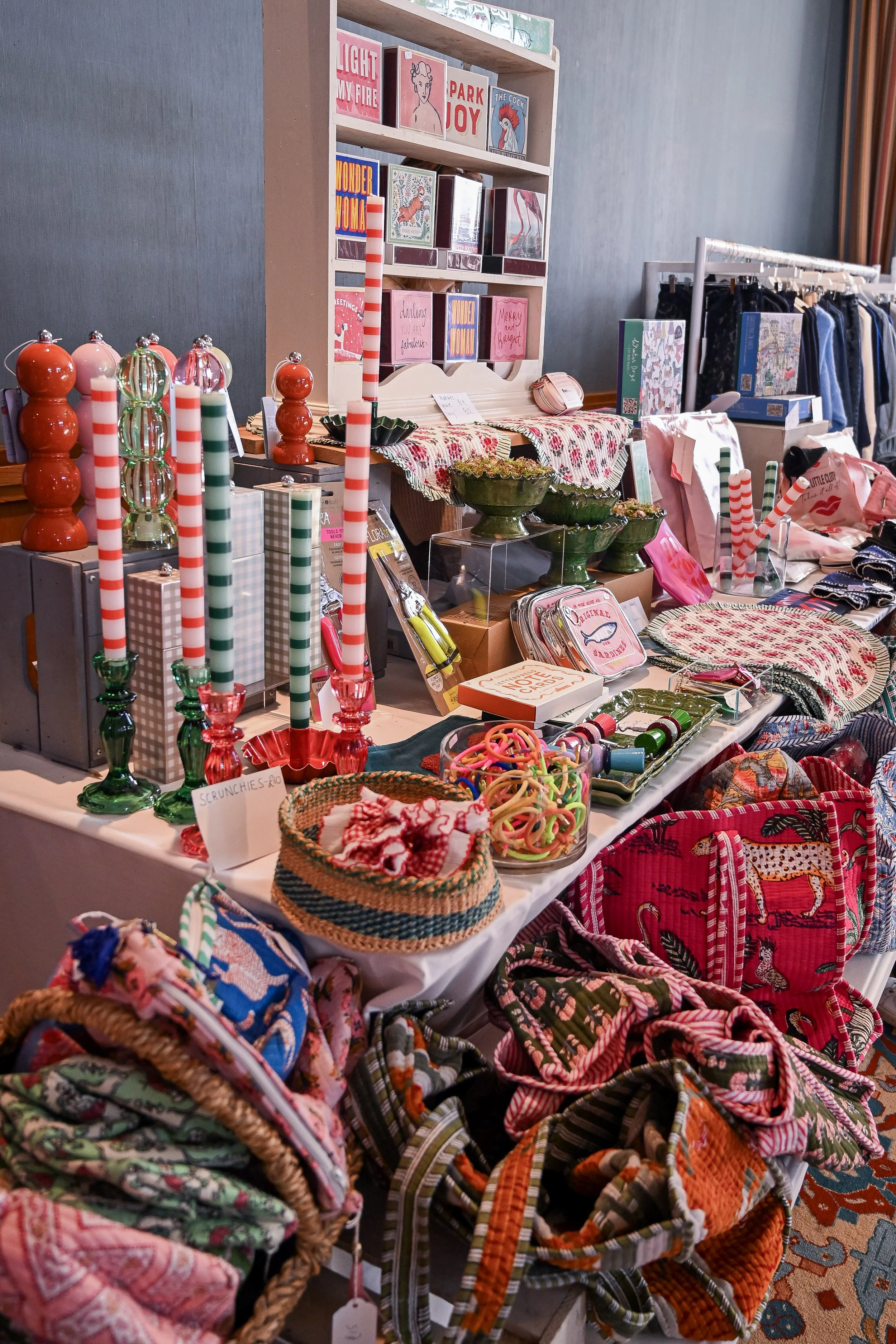 A colorful display of holiday-themed items including Christmas stockings, candles, candy canes, and festive decor at a market stall.