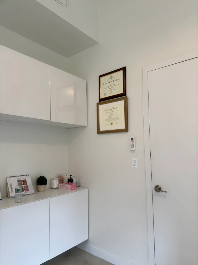 Two minimalist ceramic vases, one with dried flowers, placed on a neutral surface against a beige background.
