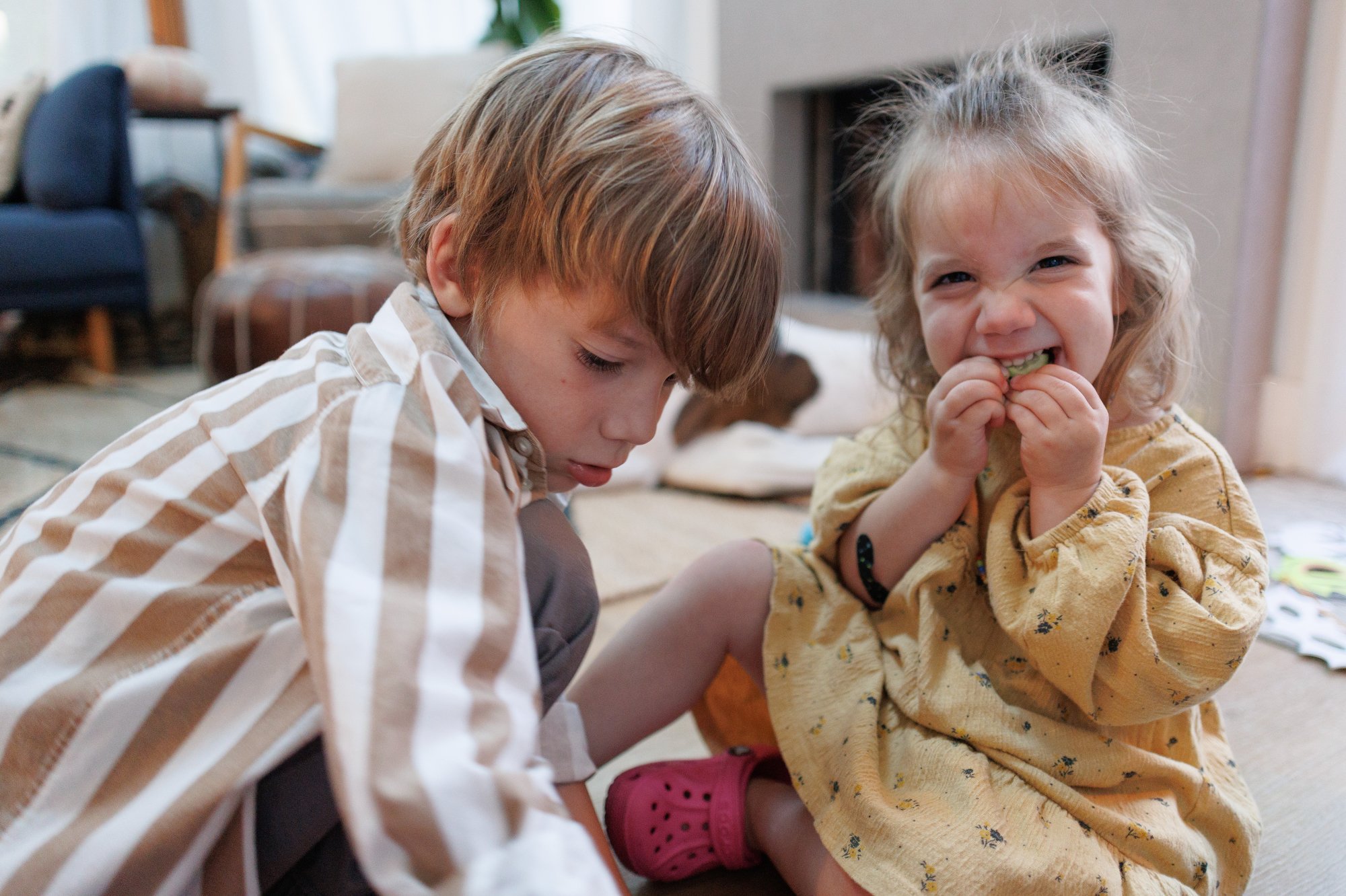 Average cost of family photos: Little girl bites on a snack with a smile while sitting next to her brother.