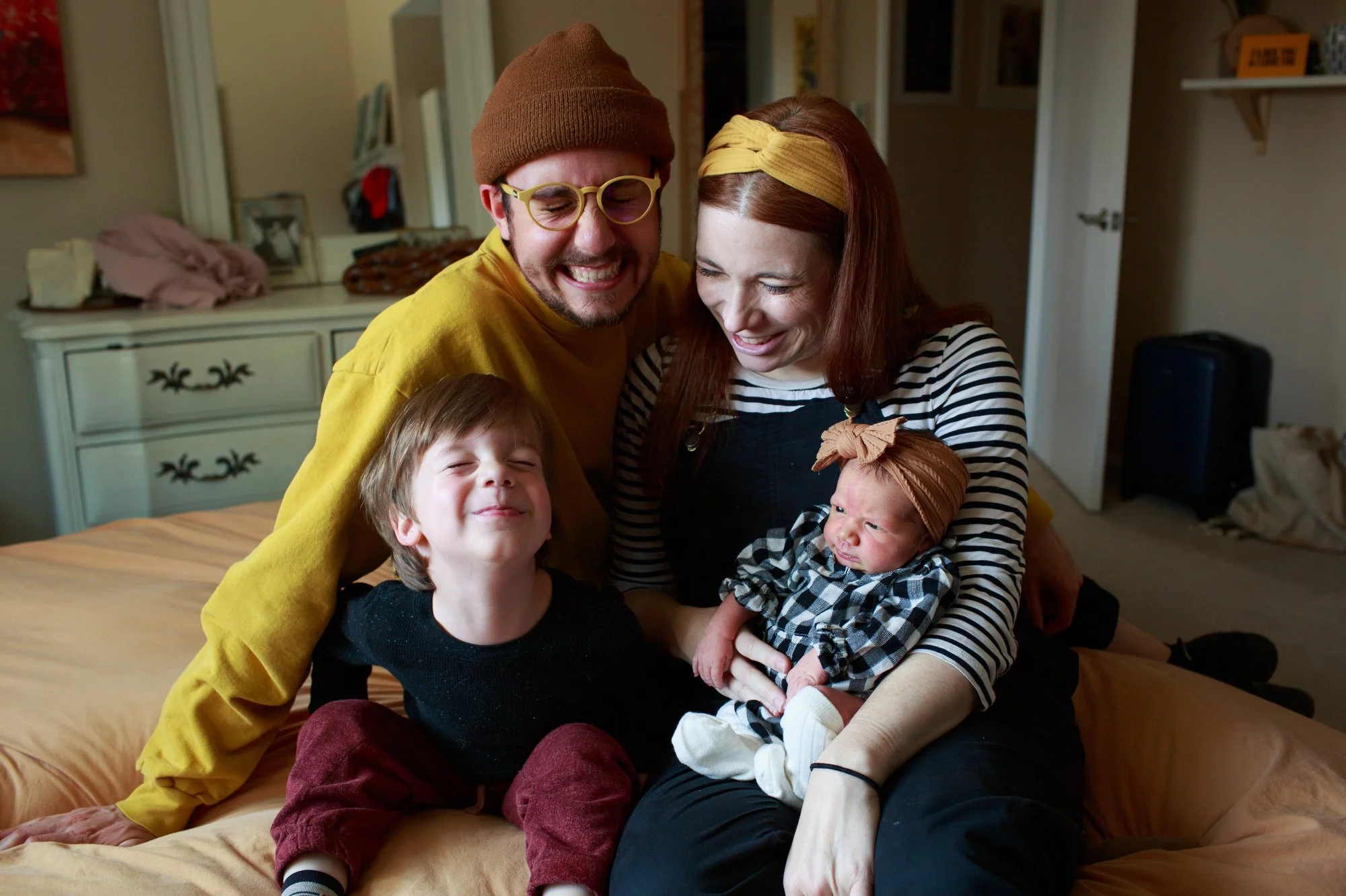 Family photoshoot outfit ideas: Family of four wears black and white with pops of yellow and burgundy. Photo by Shannon Fisher, OC newborn photographer.