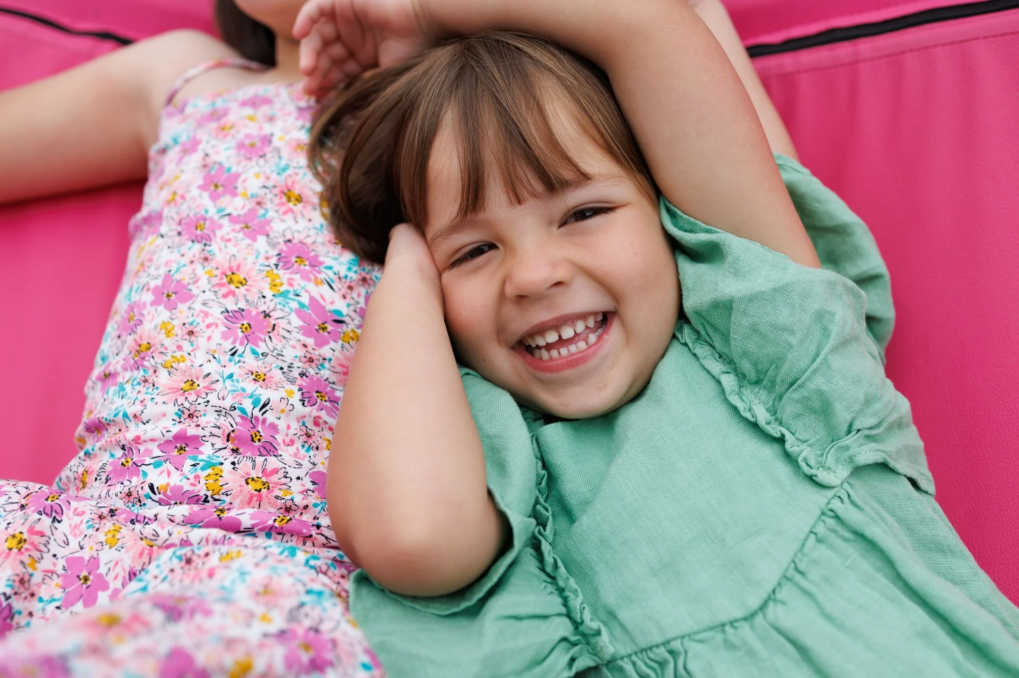 Holiday card photographer: A little girl in a teal dress with bangs smiles at the camera