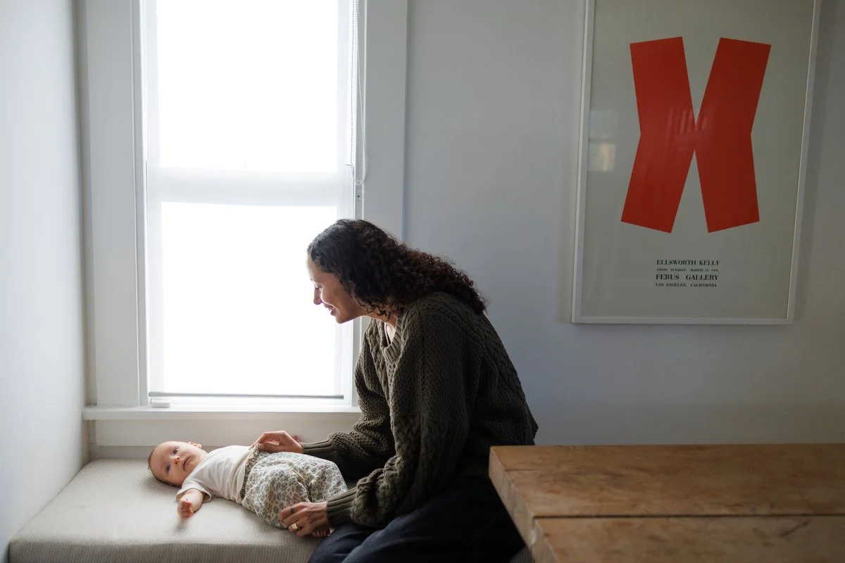 Orange County mom smiles down at three-month old newborn in an at-home documentary photo session by Shannon Fisher Photo