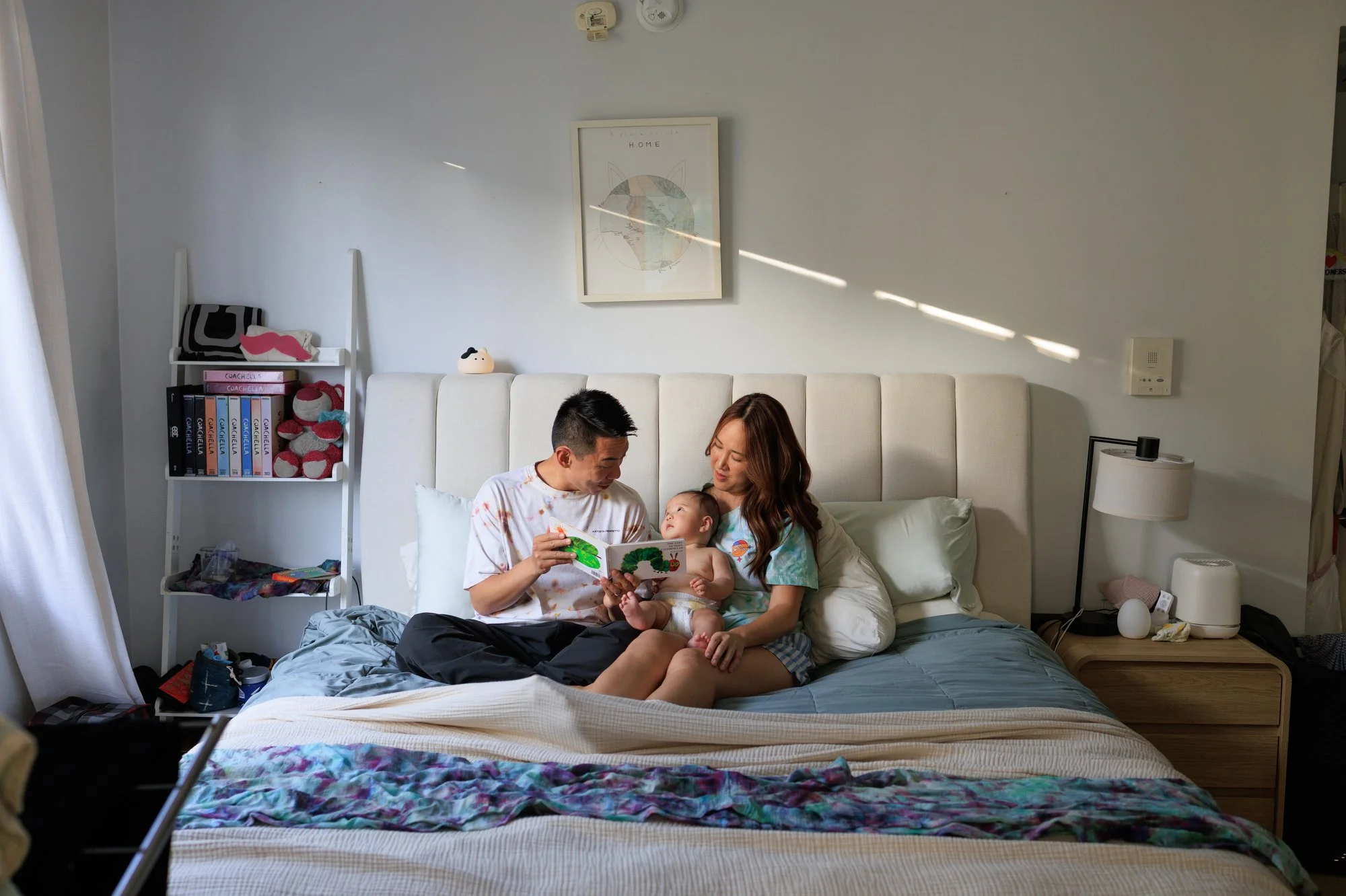 A dad reads The Very Hungry Caterpillar to baby, who is looking in his eyes. Mom holds the baby. Photo by lifestyle family photographer Shannon Fisher.
