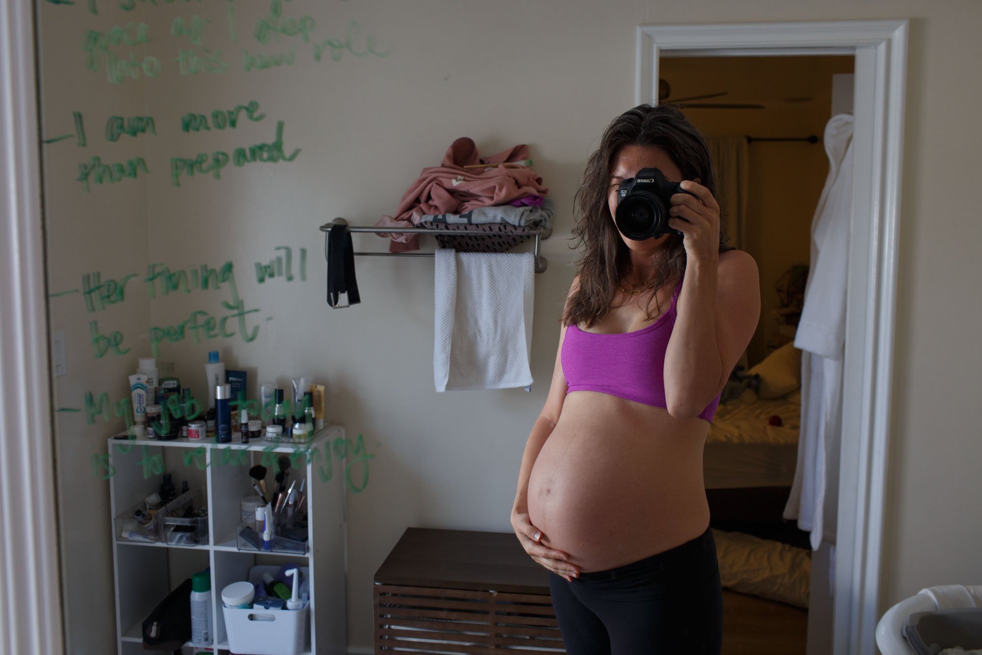 Shannon Fisher, an Orange County maternity photographer, takes a photo in the mirror holding her pregnant belly