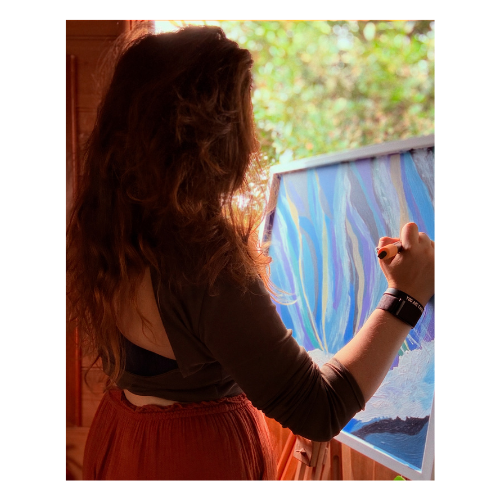 Woman painting a abstract ocean scene on an easel with trees visible through a window in the background.