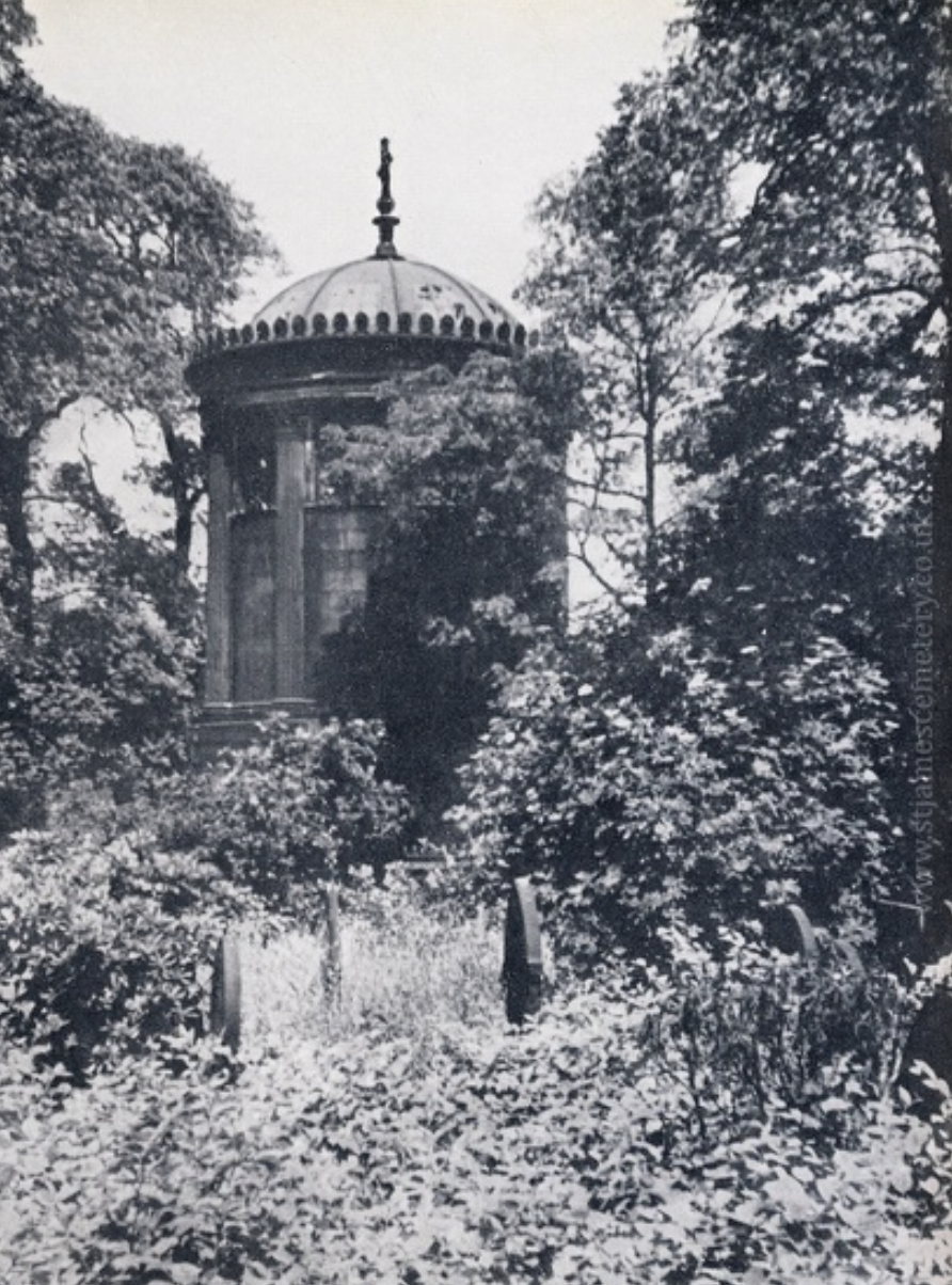Huskisson Monument, c.1955
This image shows Huskisson's mausoleum surrounded by overgrown vegetation and trees. The tops of a few other headstones are visible above the long grasses.
The mausoleum of William Huskisson was designed by John Foster Jr a