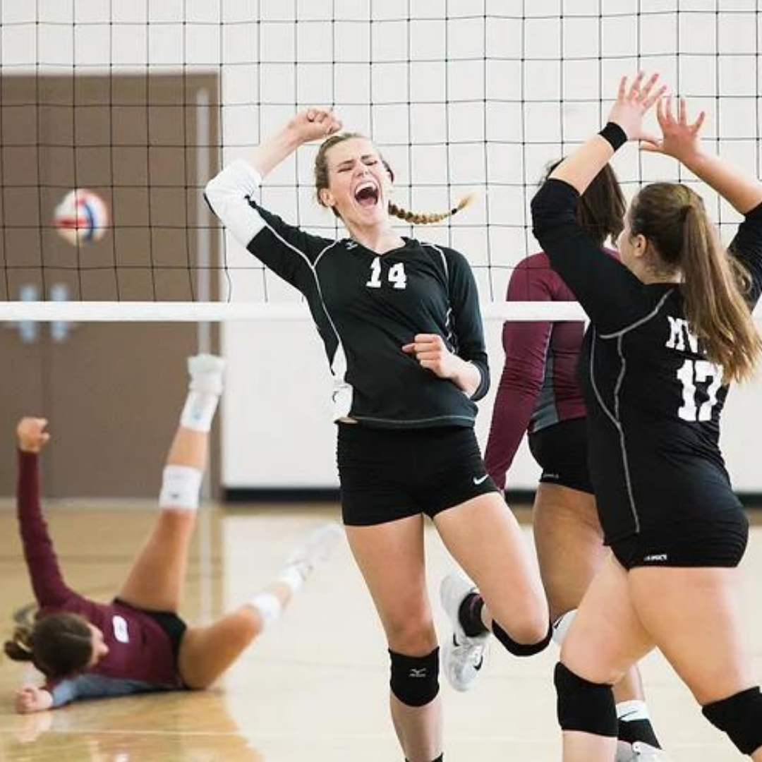 A volleyball player celebrating with her team after winning a point.