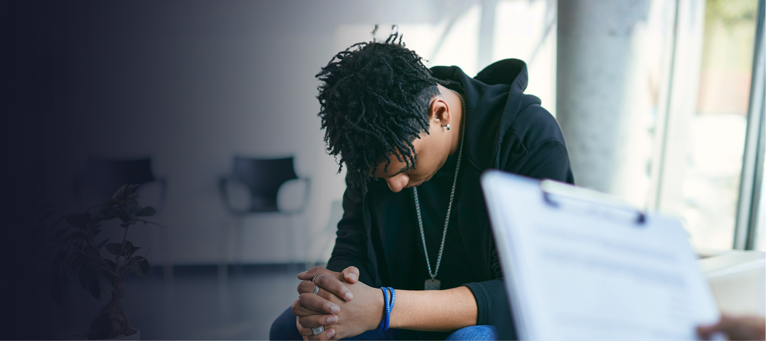 Image of a boy with black hair with his head down looking discouraged.