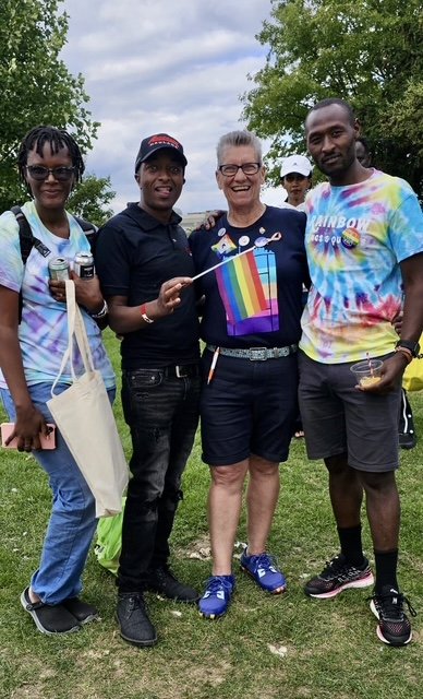 Deirdre Pike with a group of people, holding a pride flag