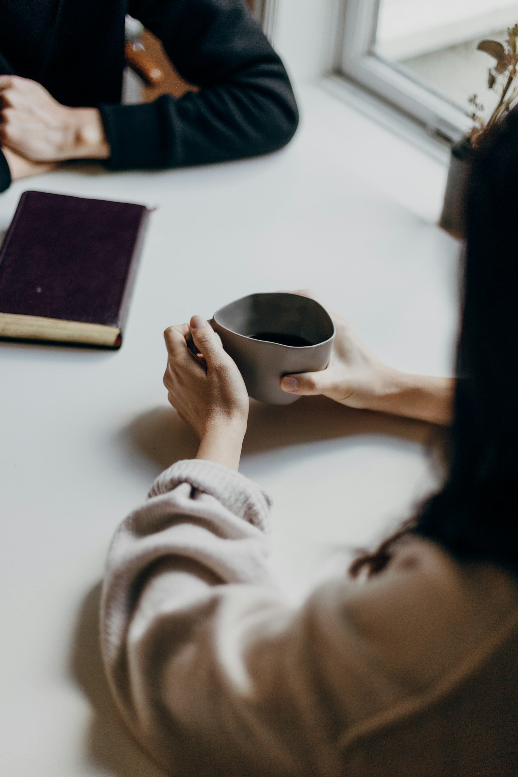 Woman holding misshapen coffee mug sitting at table
