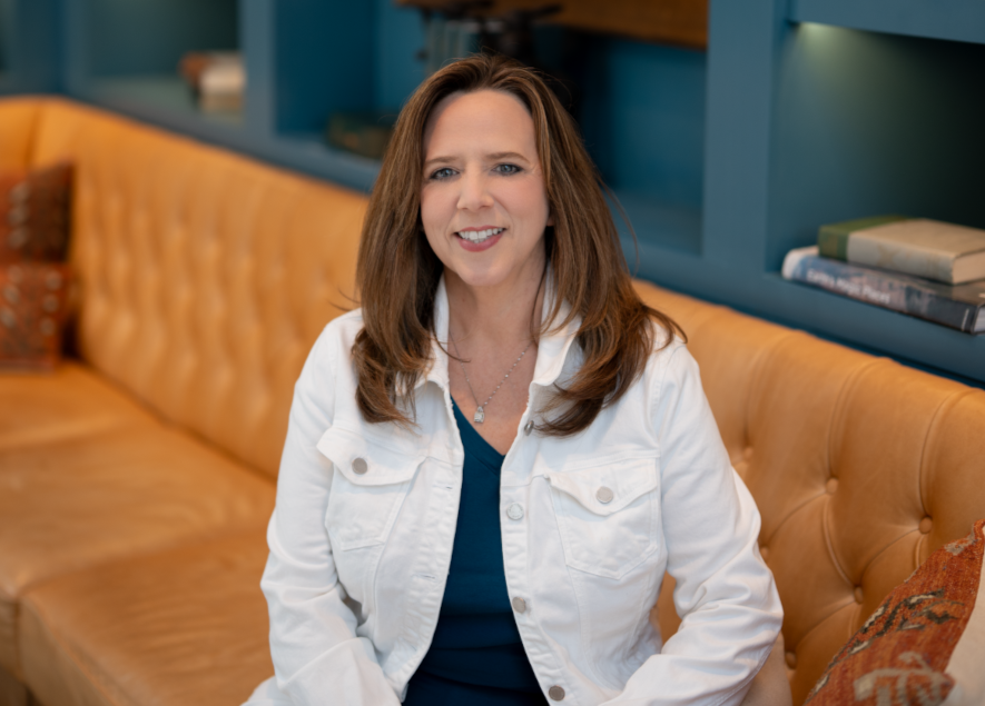 Deborah Everson sitting on a tan leather sofa in a cozy room.