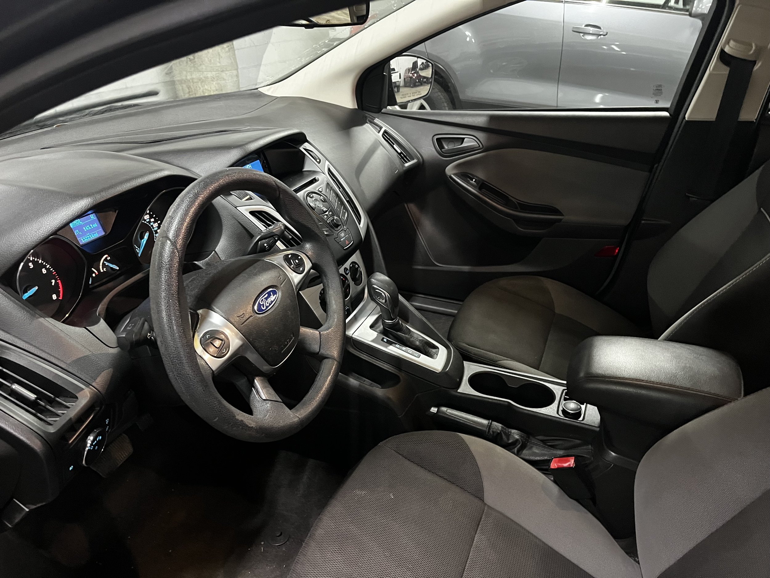 Interior view of a Ford car showing the steering wheel, dashboard, and front seats.