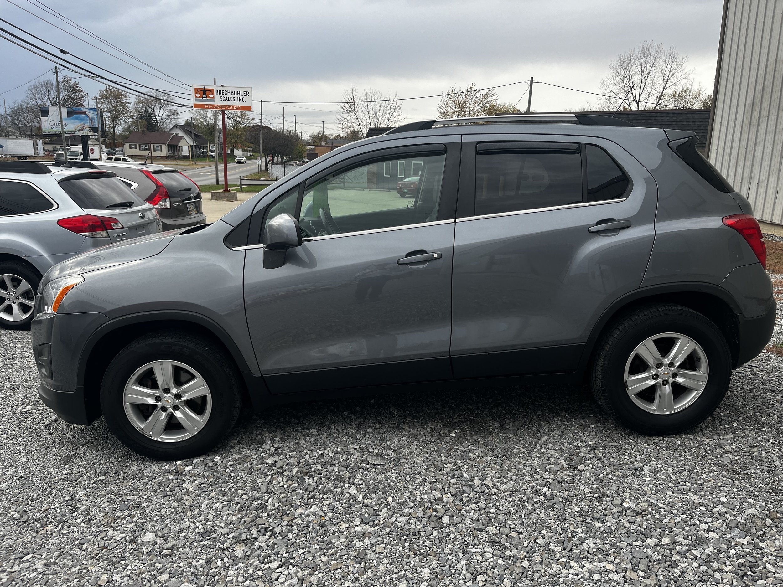 Side view of a gray SUV parked on a gravel lot.