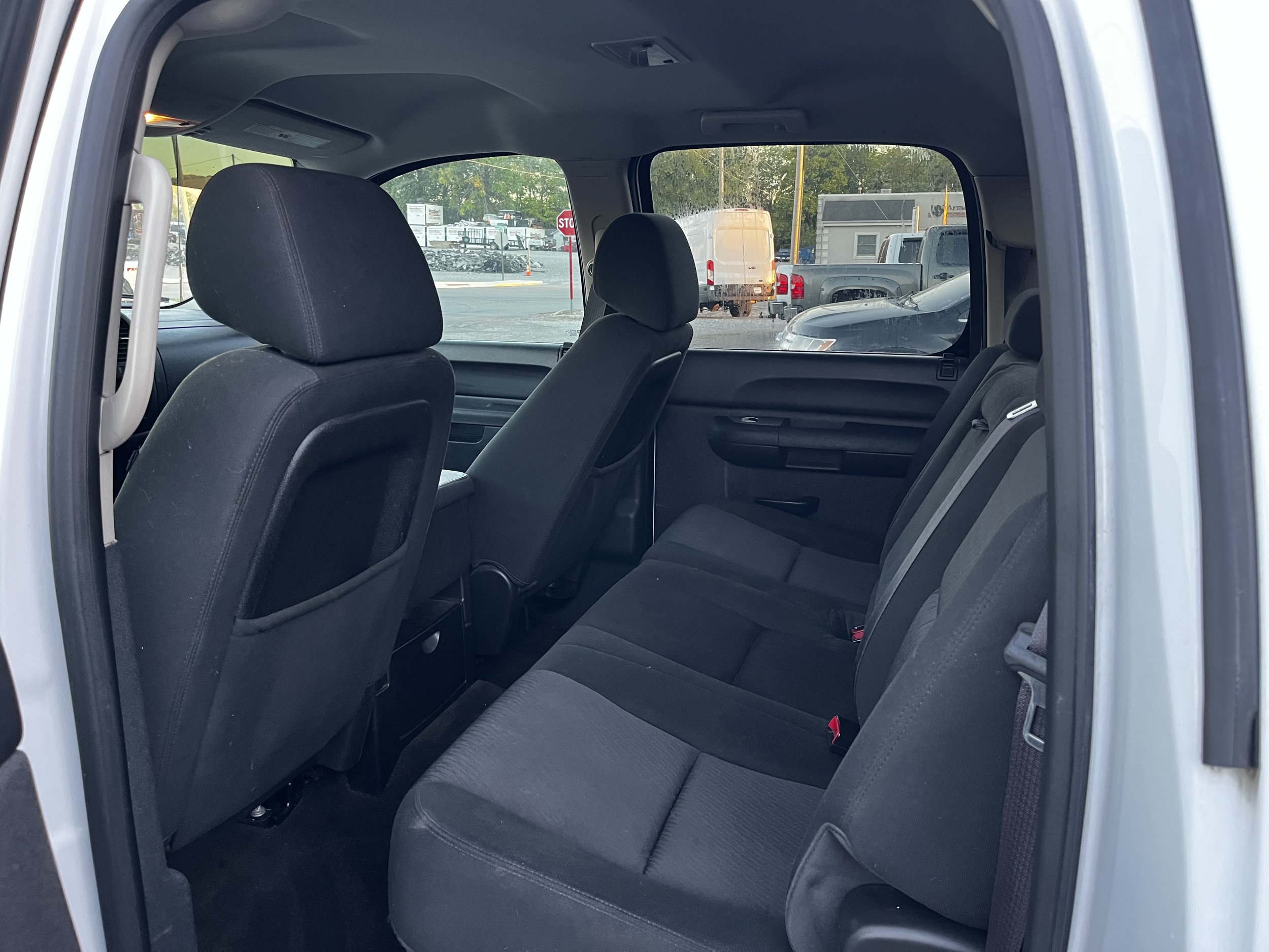 Interior view of a car's rear seats with black upholstery, visible from the open rear door.