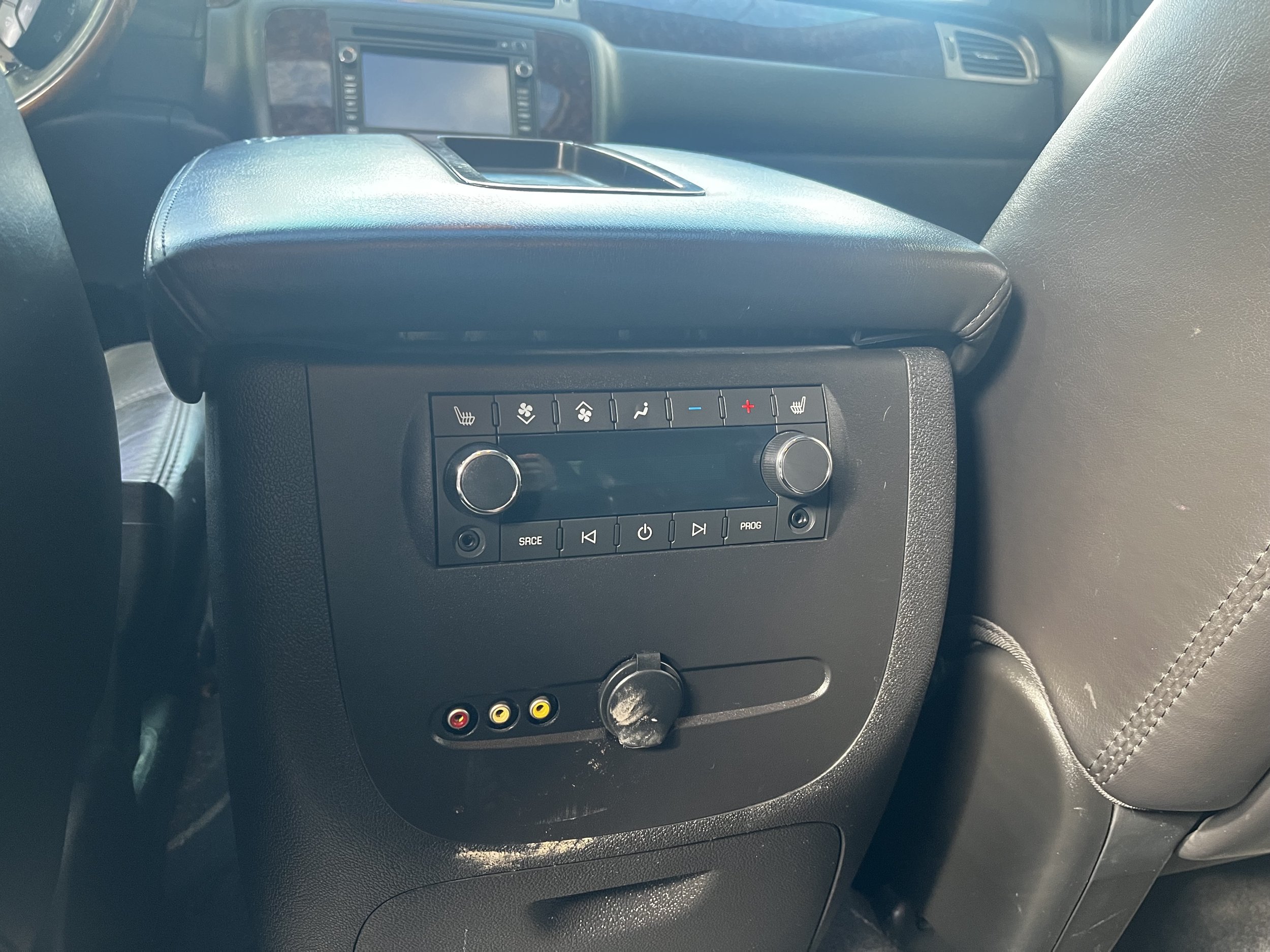 Rear seat entertainment console in a vehicle showing climate control buttons and AV inputs.
