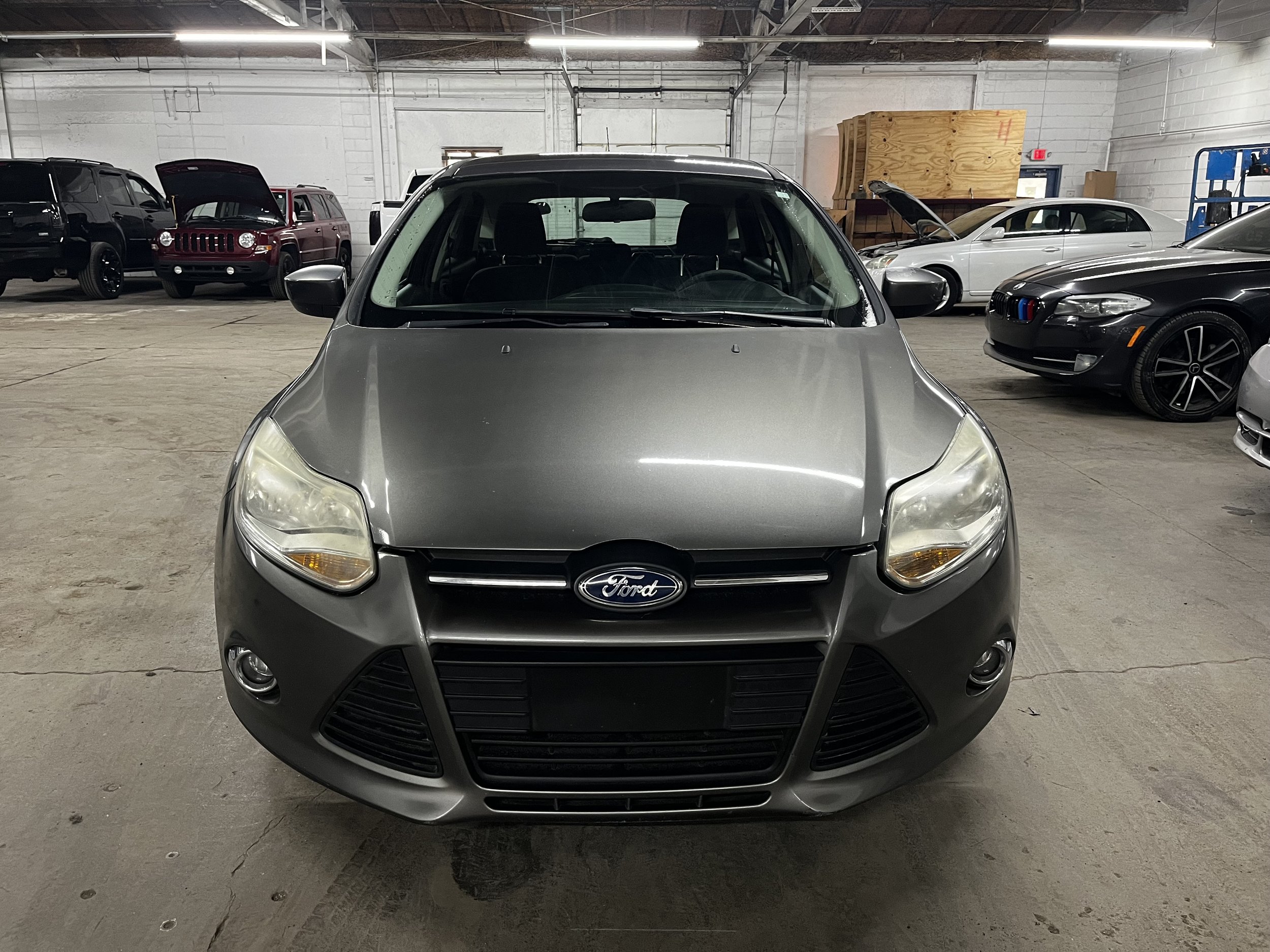 Gray Ford car front view in a garage with other vehicles