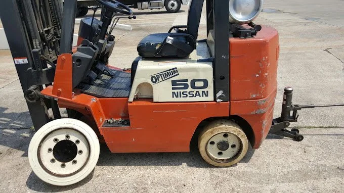 Orange and white Nissan forklift with the word 'OPTIMUM' and the number '50' on its side, parked on concrete.