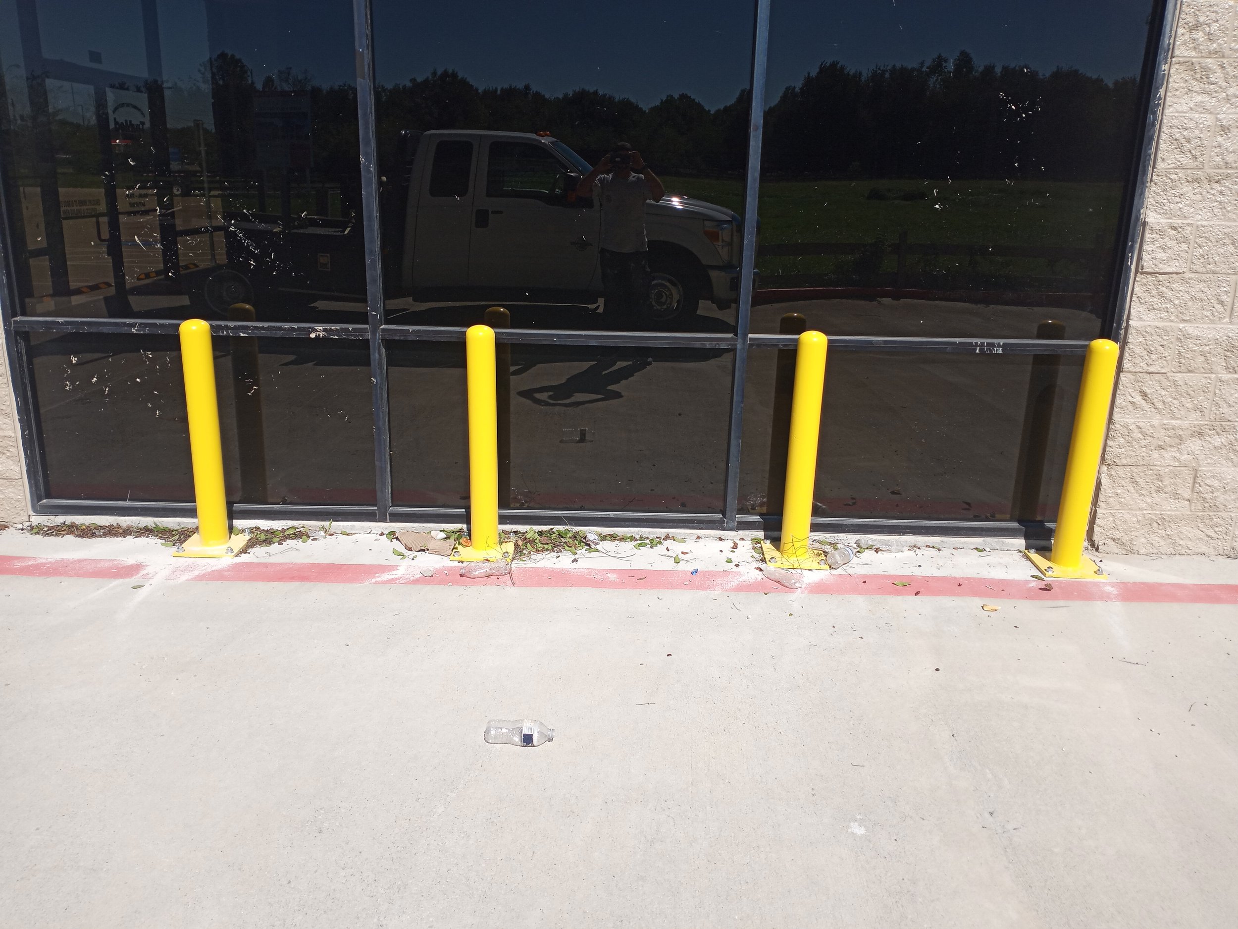 Four inch bolt down bollards protecting storefront windows