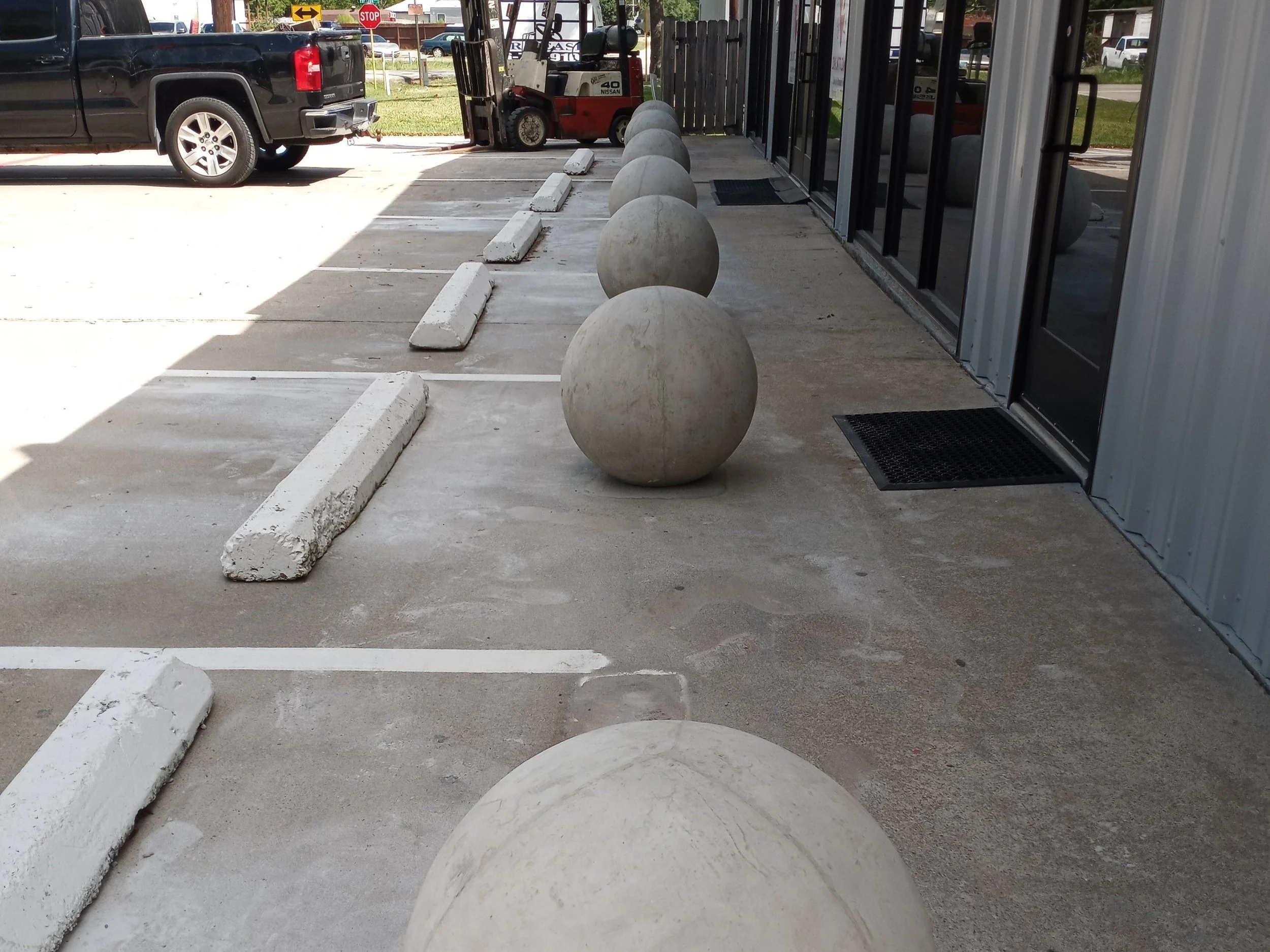 Cast concrete spherical bollards protecting a business storefront.