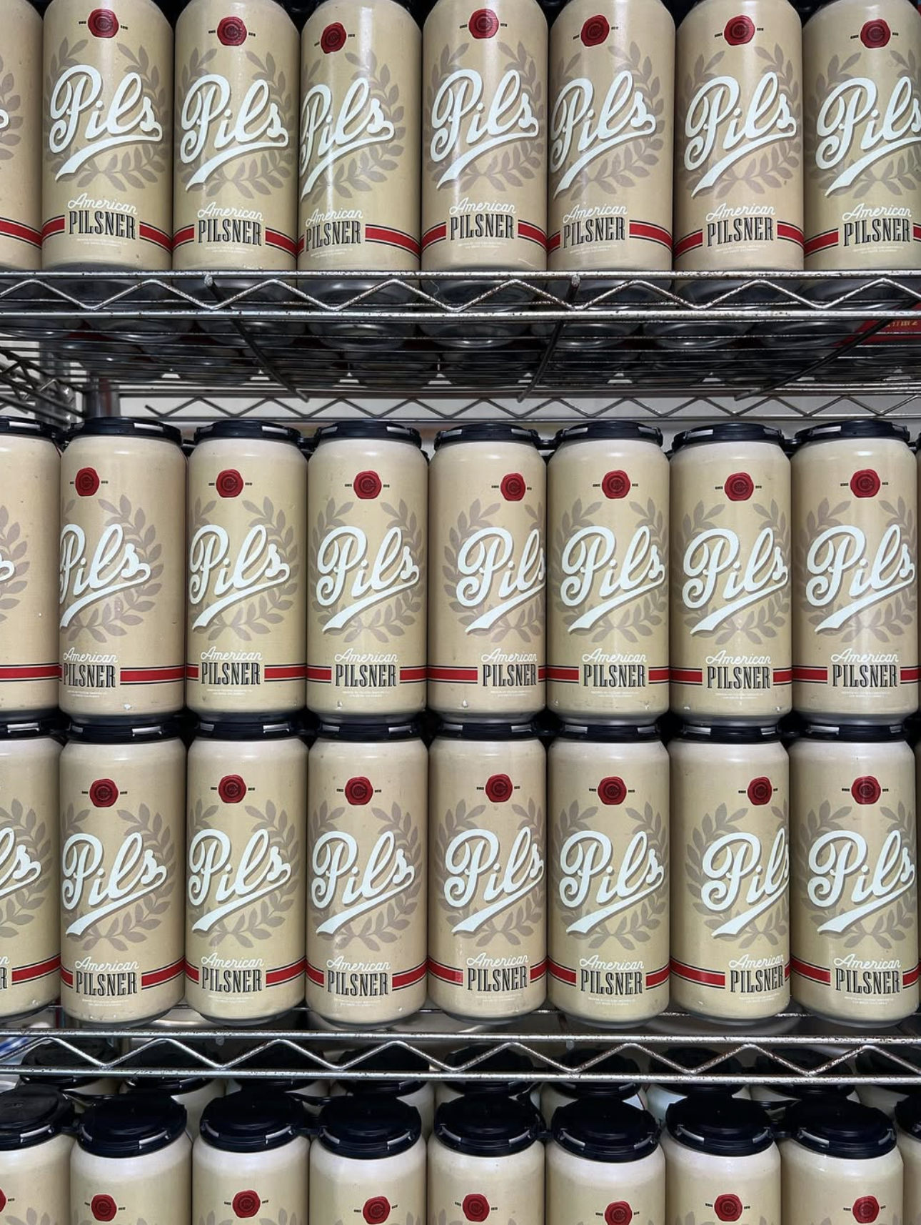 Rows of cans of American Pilsner beer on store shelves.