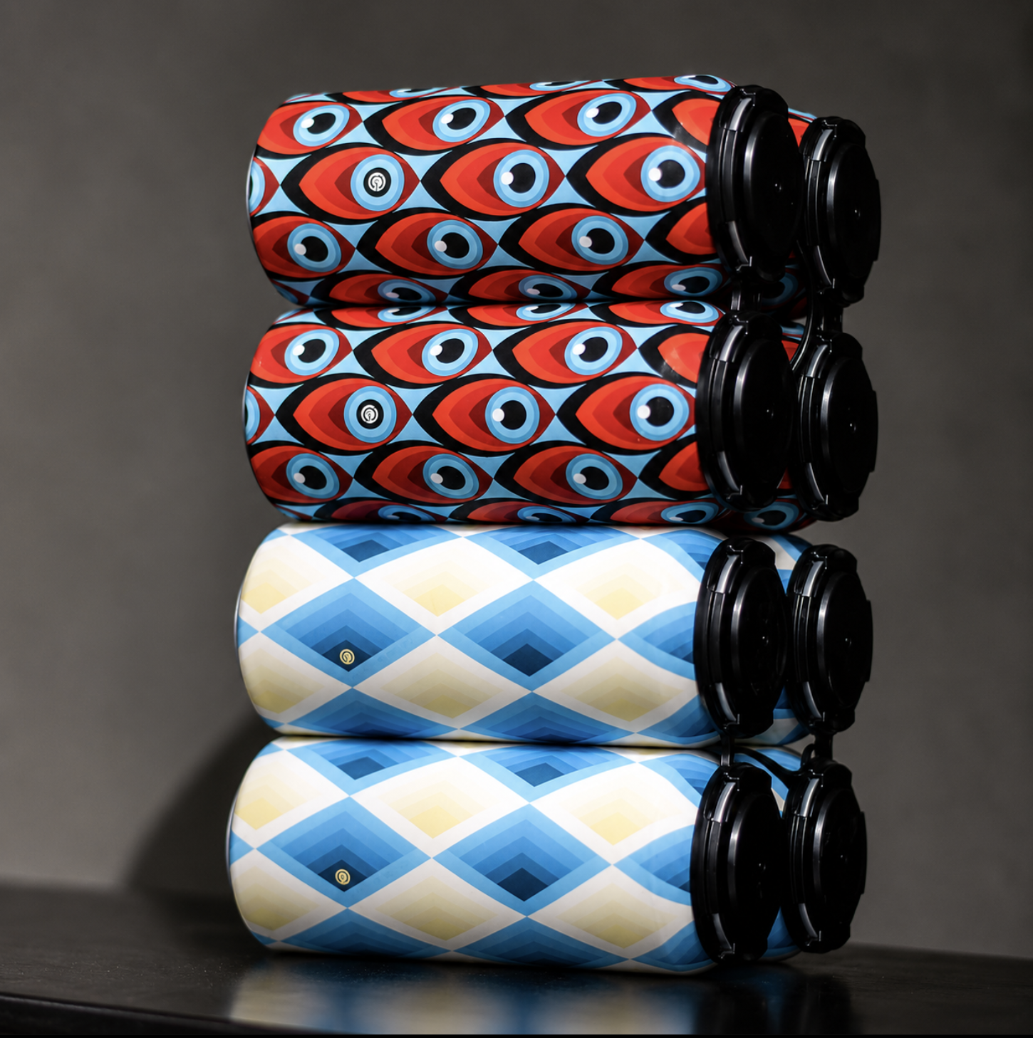 Three rolls of wrapping paper stacked on top of each other, with colorful and patterned designs, on a dark surface.