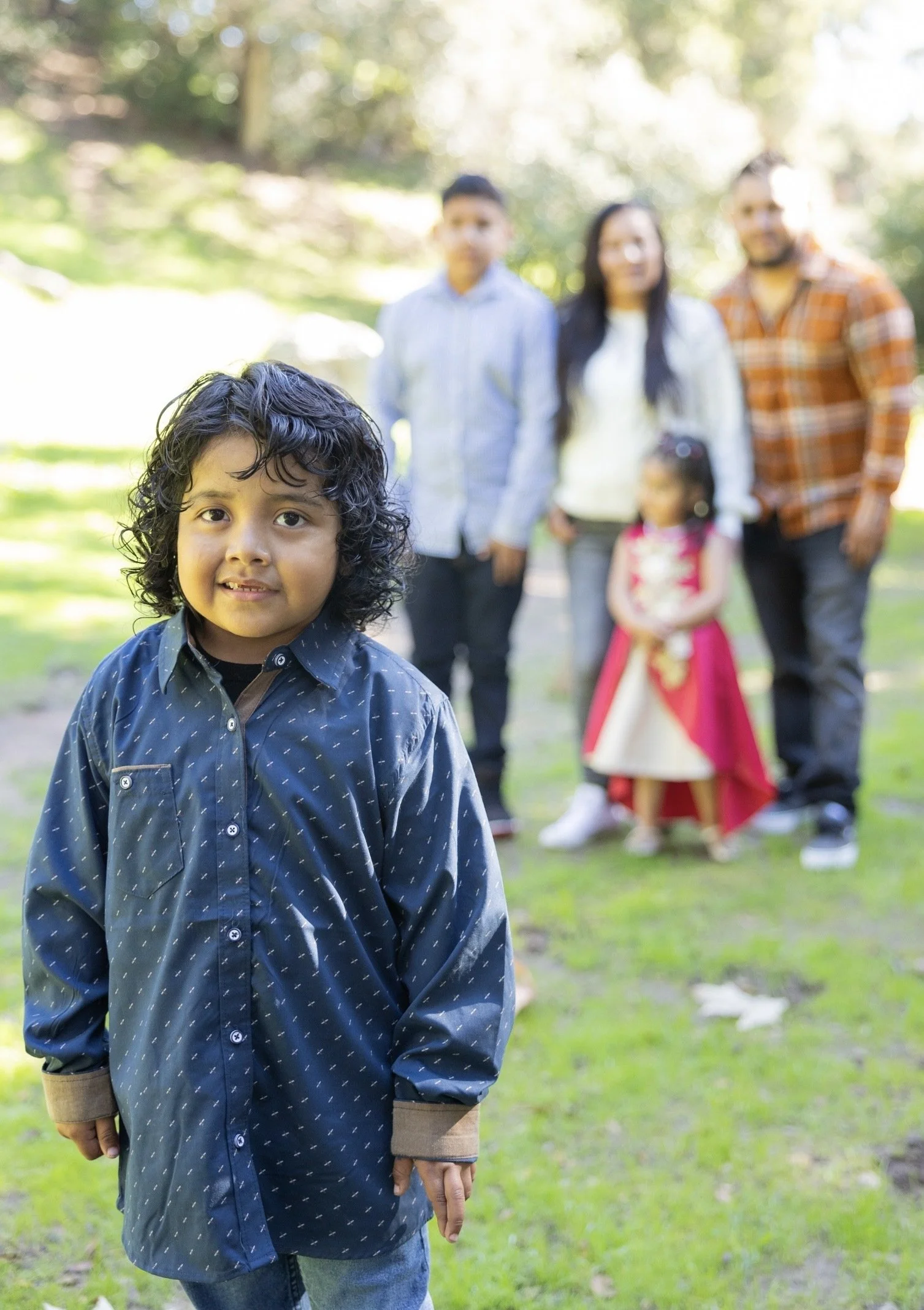 Child in blue shirt posing in front of family