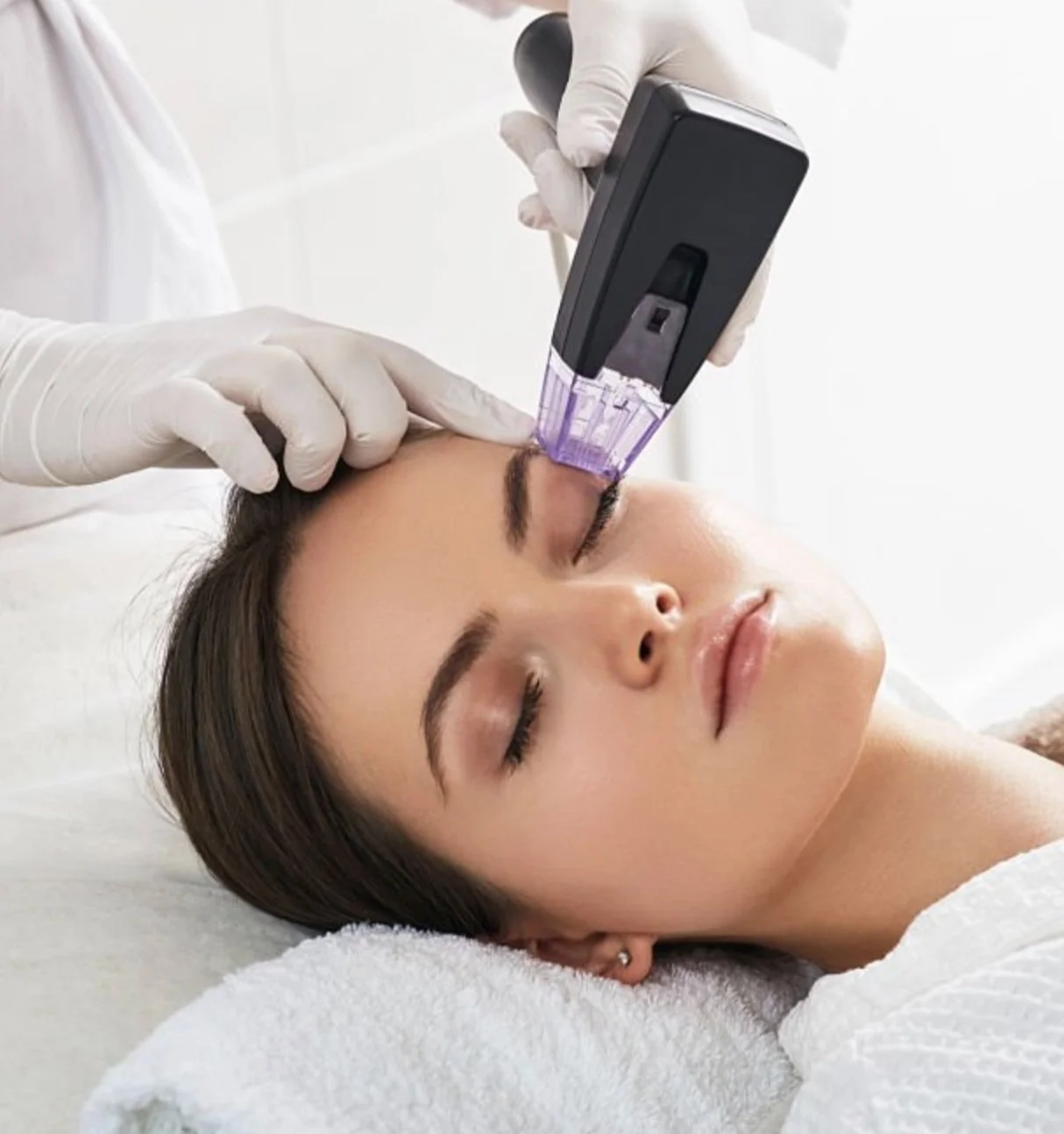 Person receiving a skin treatment with a handheld device on the forehead.