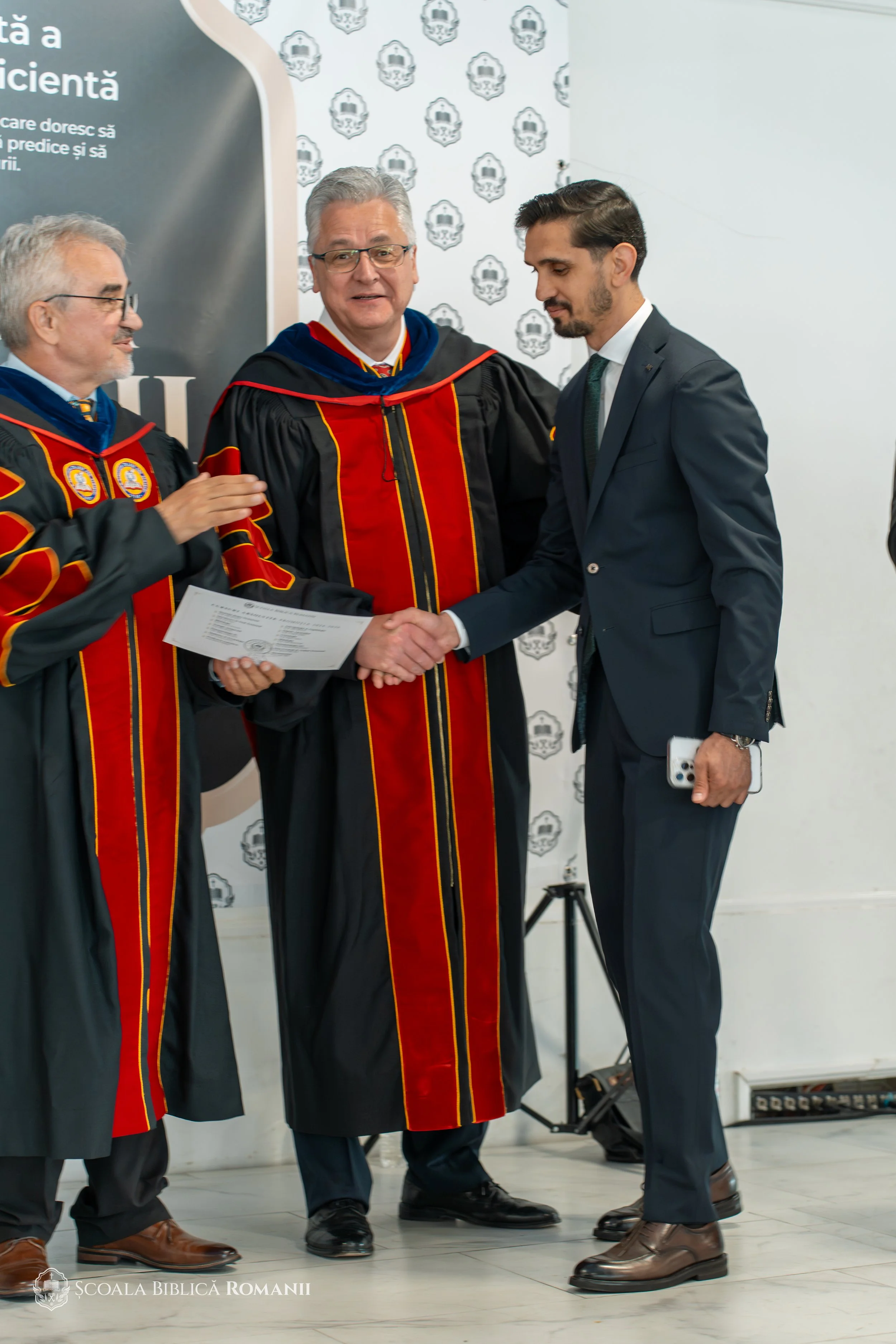 Absolvent cu diploma, alături de profesorii școlii.
