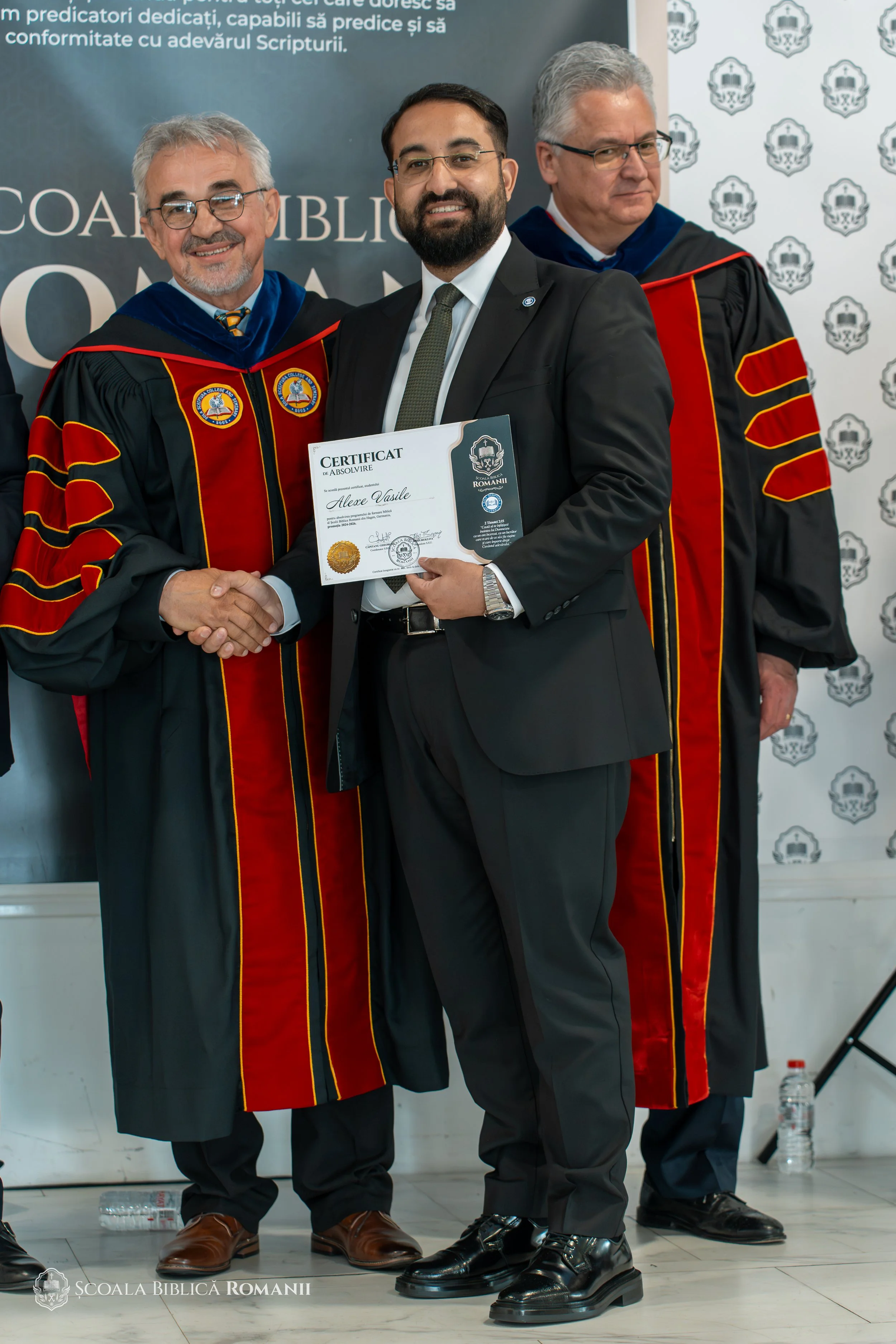 Absolvent primind diploma și felicitările profesorilor.