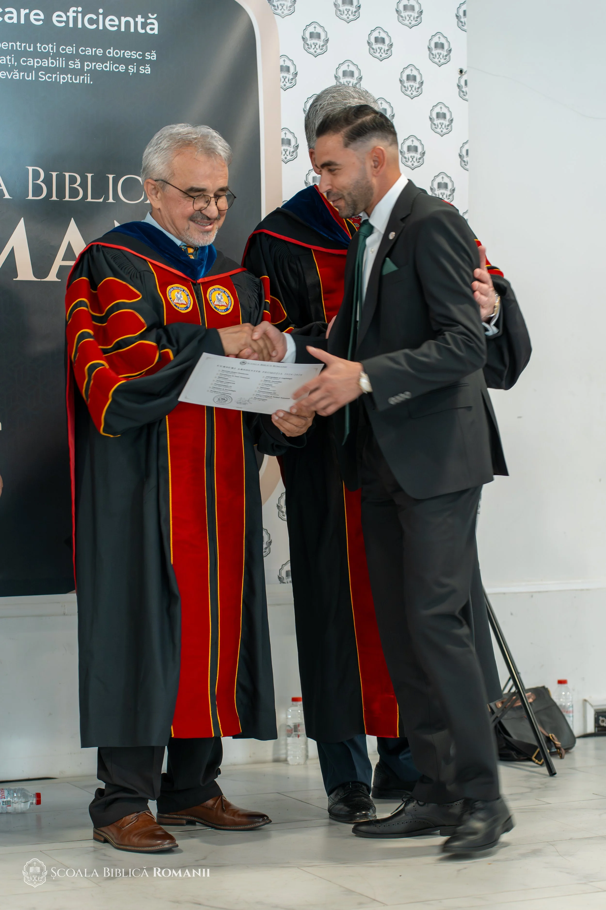 Absolvent primind diploma și felicitările profesorilor.
