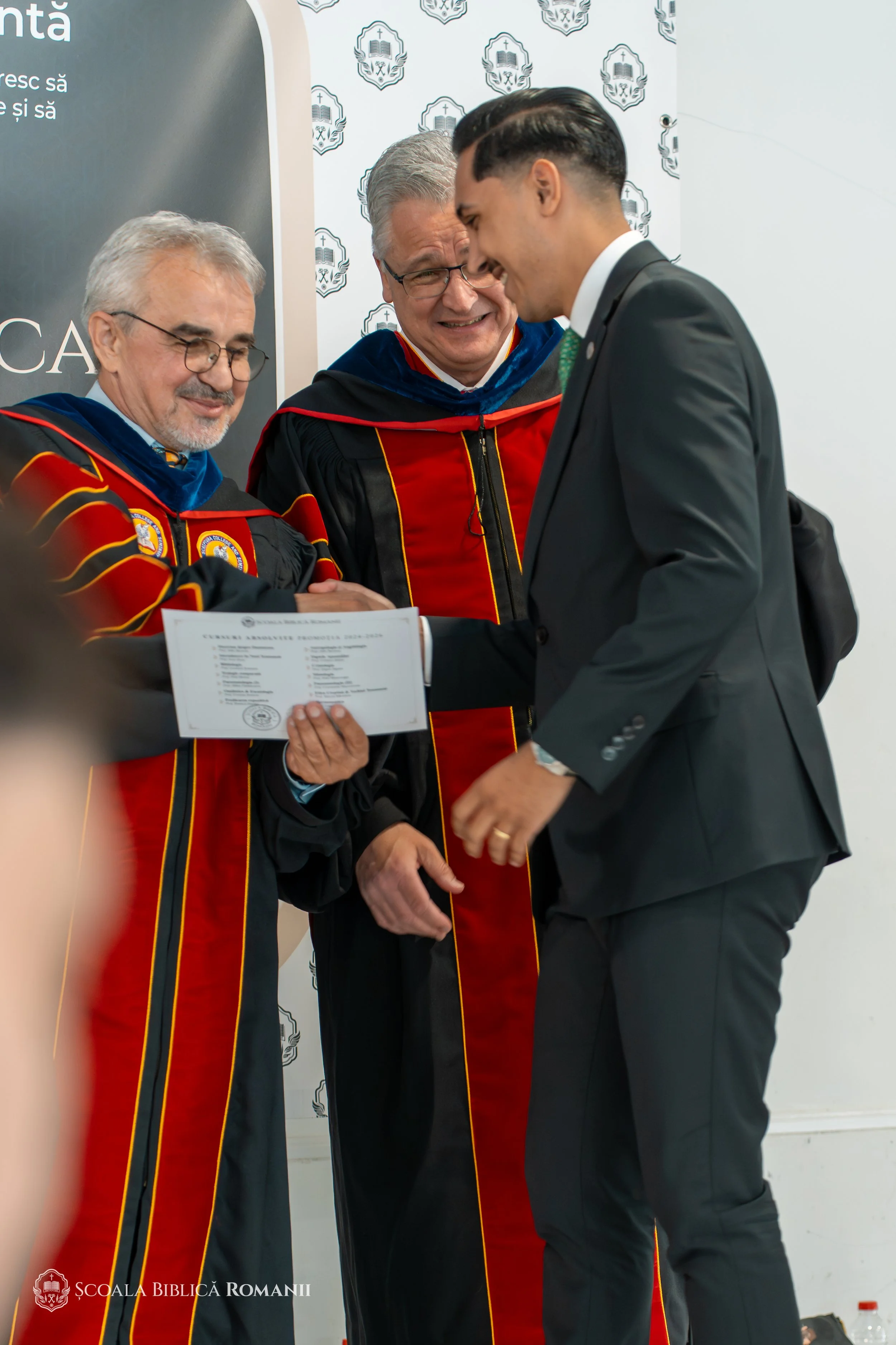 Profesori și absolvent cu diploma, la ceremonia din Hagen.