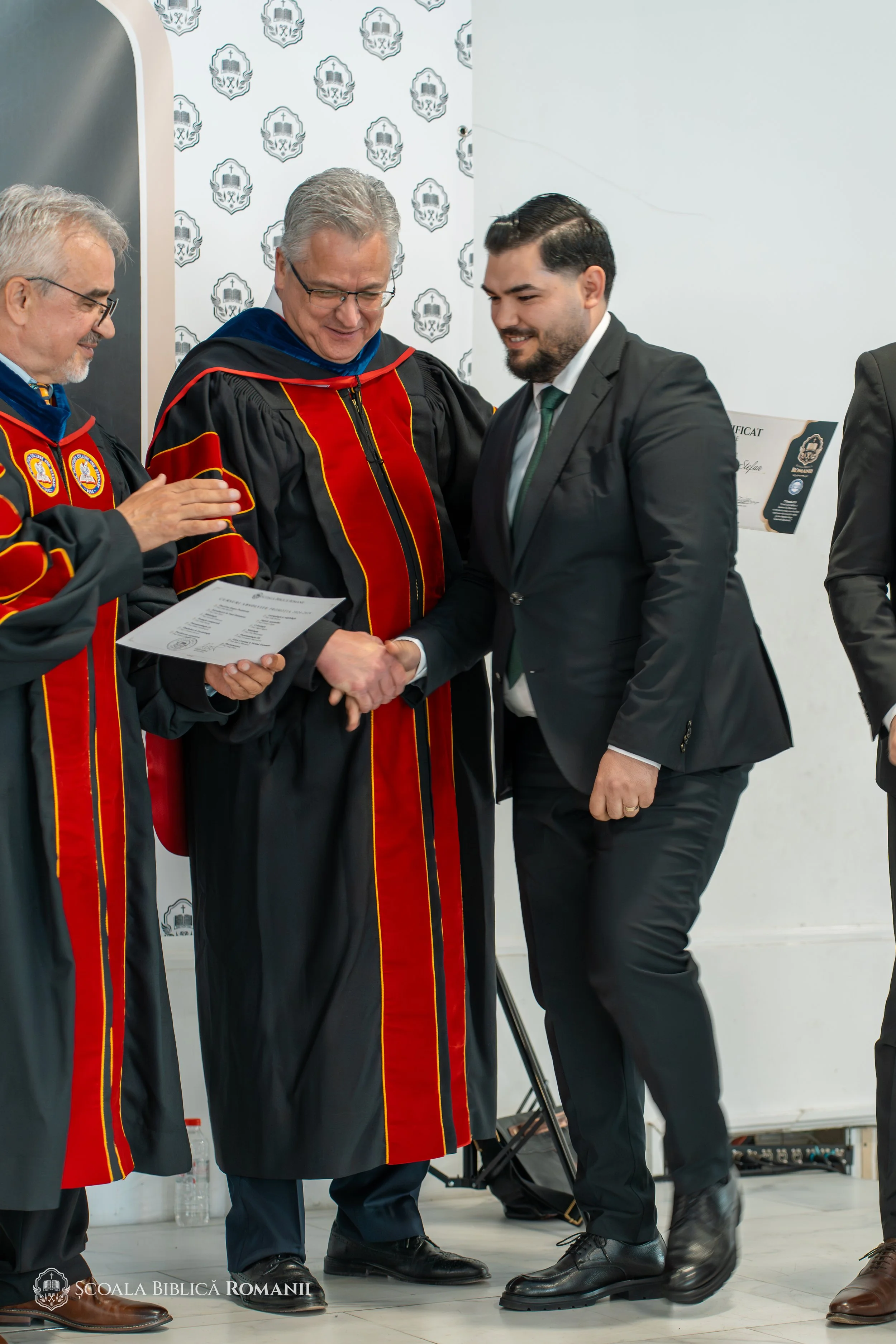 Reprezentanții școlii felicită un absolvent la înmânarea diplomei.