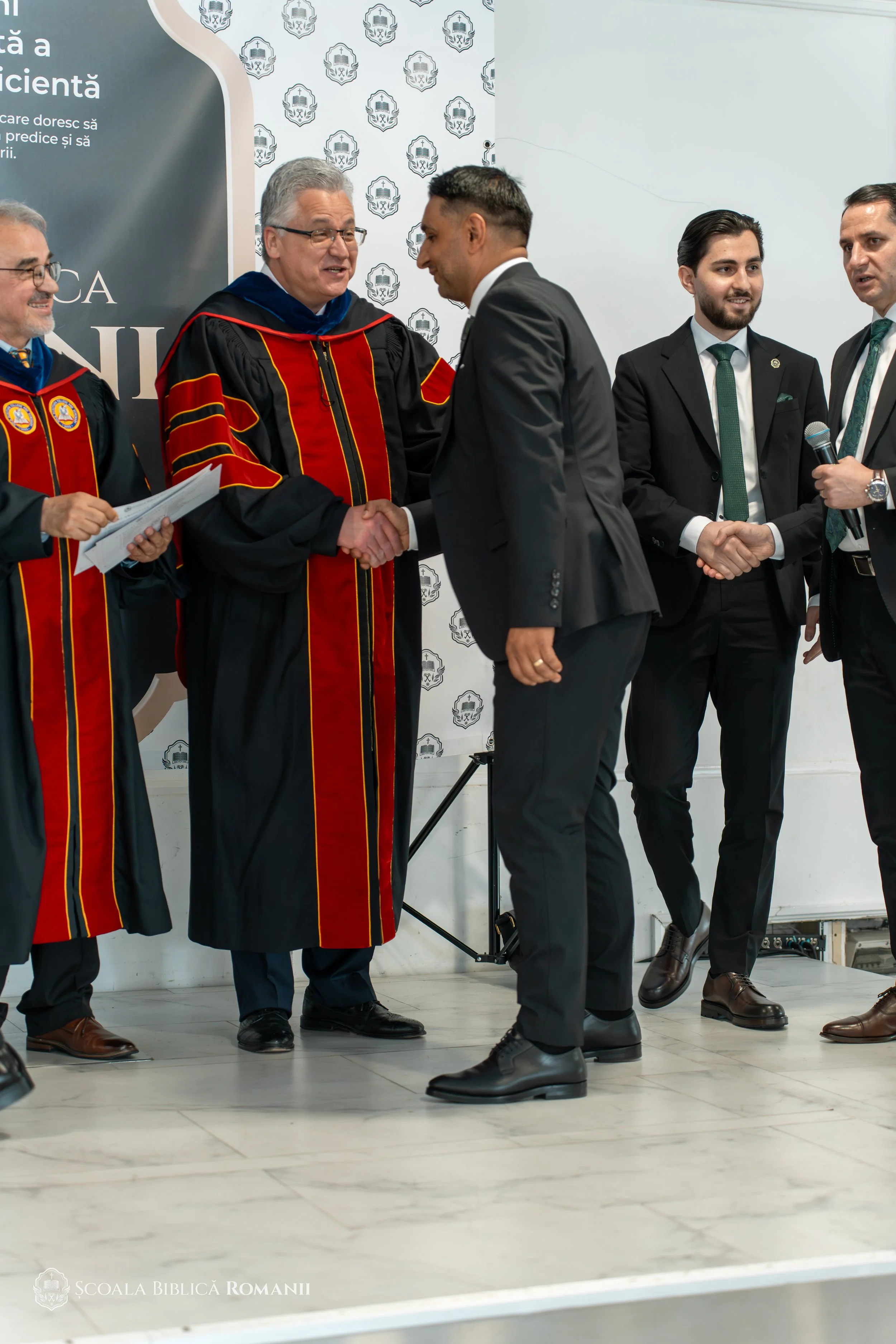 Profesori în robe academice felicitând un absolvent.
