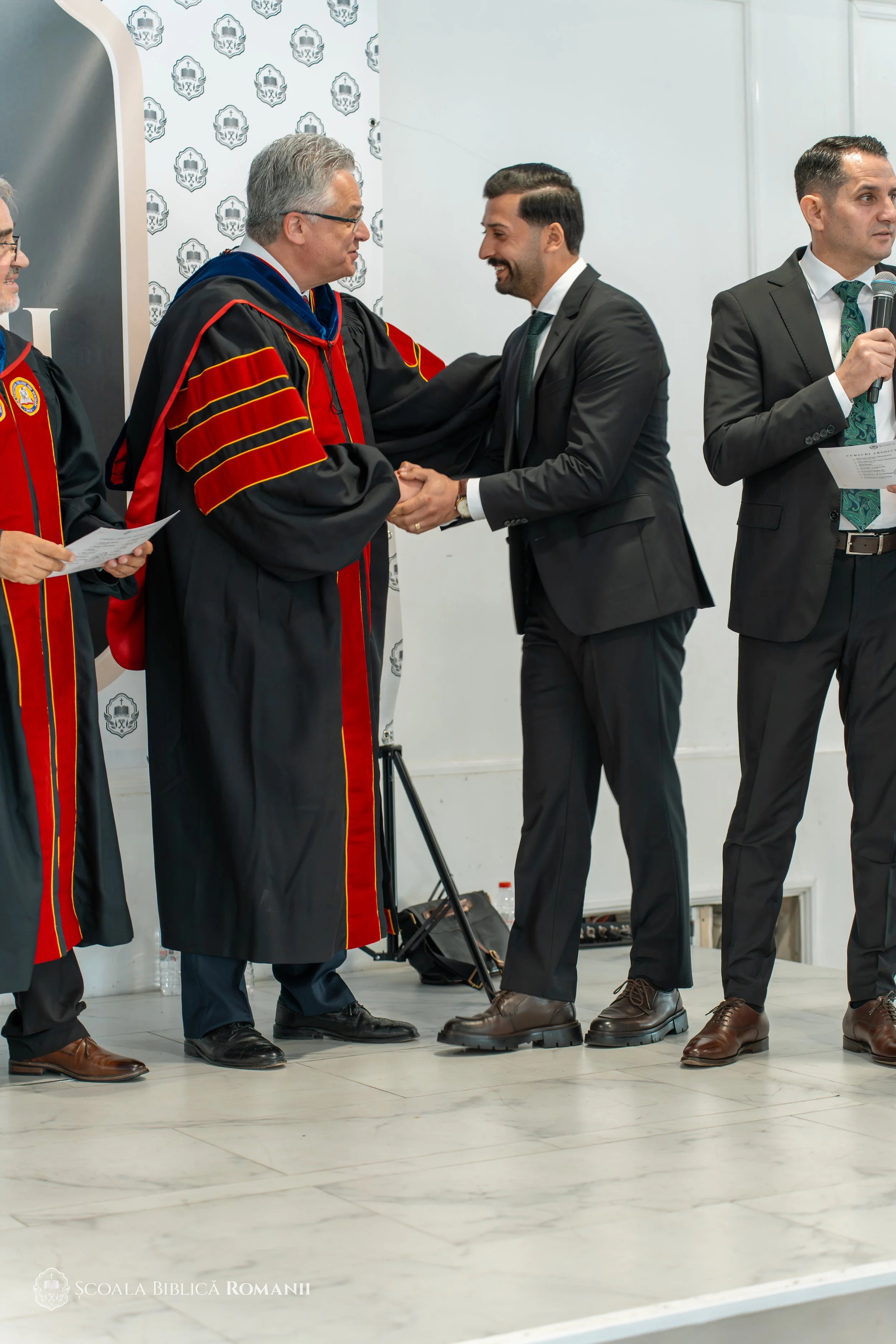Profesor felicitând un absolvent în timpul ceremoniei.