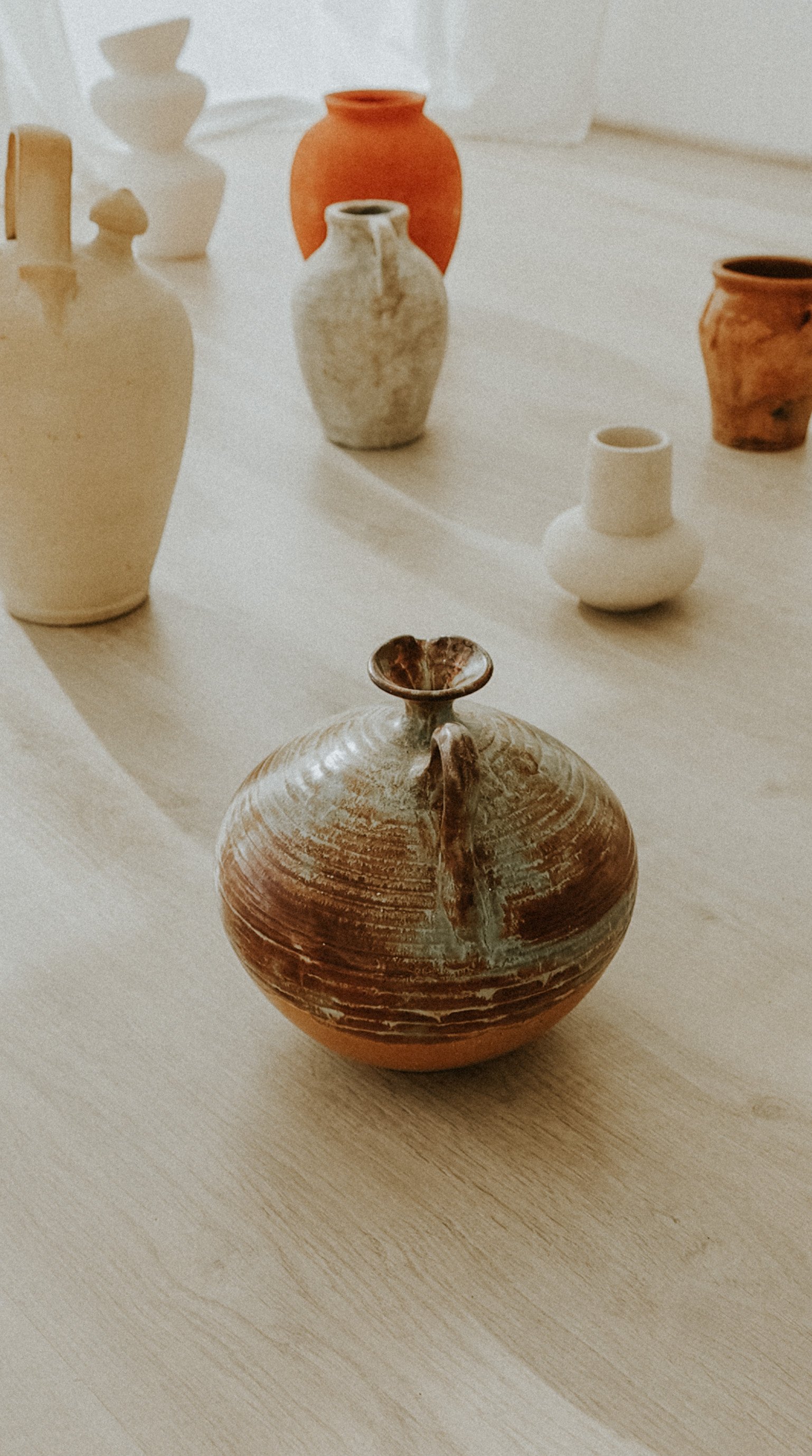 Vasos y cerámicas de varios tamaños y colores sobre una mesa de madera.