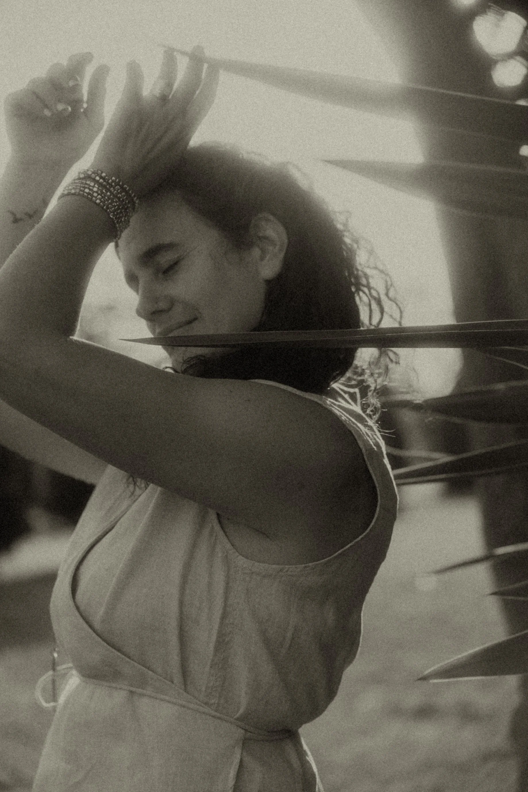 Mujer sonriendo con ojos cerrados, sosteniendo un objeto largo, en un entorno interior.